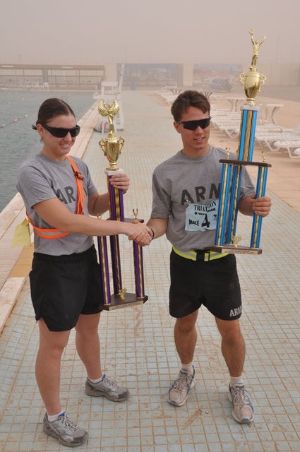 1st Lt. Samantha Holys, 16th Special Troops Battalion, 16th Sustainment Brigade, and 1st Lt. Marshall Kulp, 574th Quartermaster Co., 30th Combat Sustainment Support Battalion, 16th Sust. Bde, show off their respective first place trophies after winning the Bushmaster’s Triathlon. Holys finished first in the women’s division with a time of one hour and seven minutes. Kulp finished first in the men’s with an overall time of 53 minutes and seven seconds. The race consisted of a 400-meter swim, an 11K bike and a 3K run.
