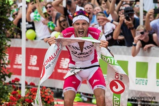 An ecstatic Jan Frodeno crosses the finish line after setting a new world record for fastest iron-distance triathlon. Photo Credit: Paul Phillips