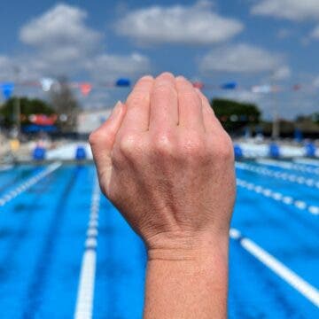 A swimmer demonstrates a cupped hand position for swimming