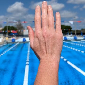 A swimmer demonstrates a gapped hand position for swimming