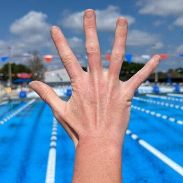 A swimmer demonstrates a wide hand position for swimming