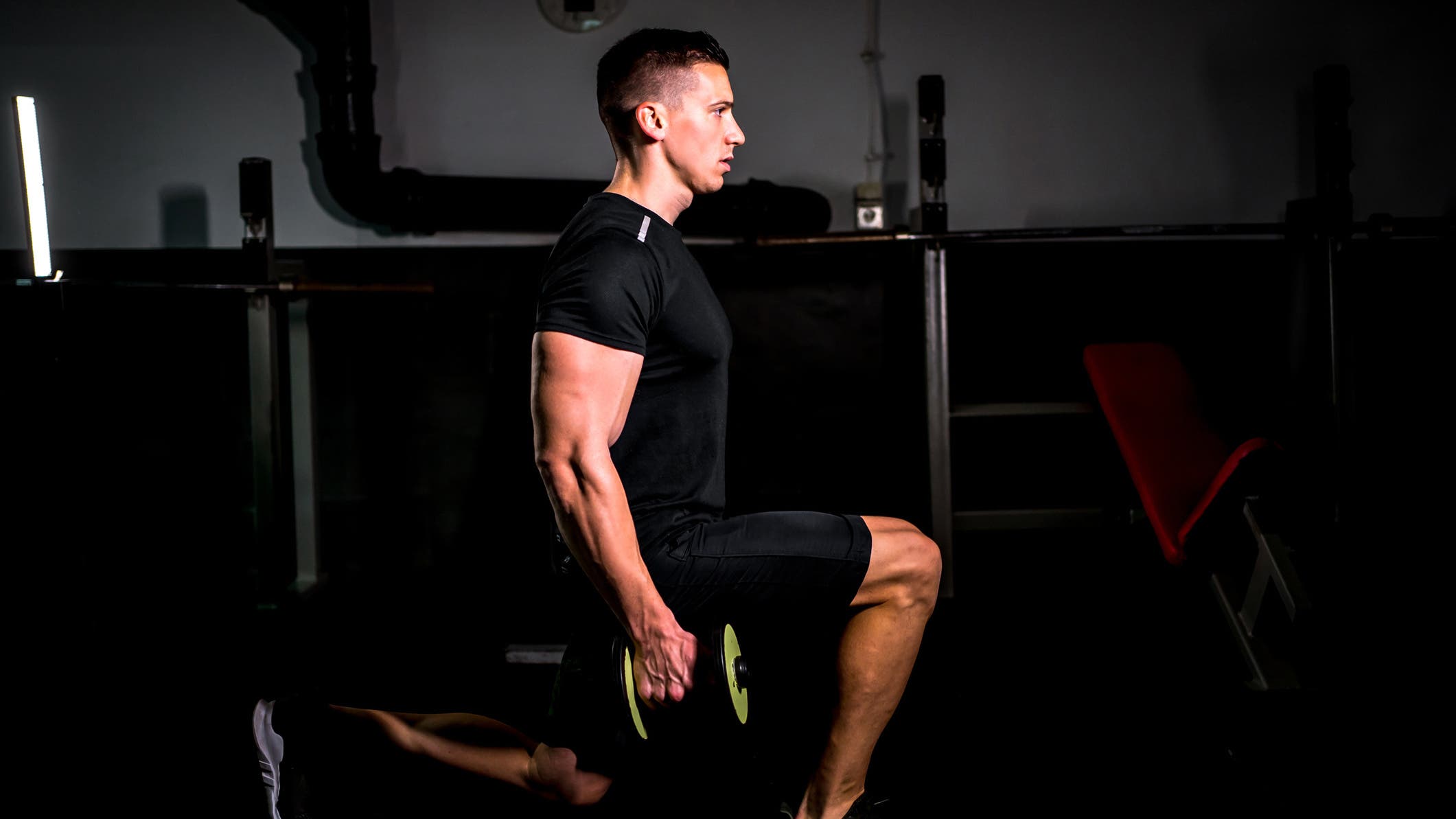 A man demonstrates a walking lunge with dumbbells.