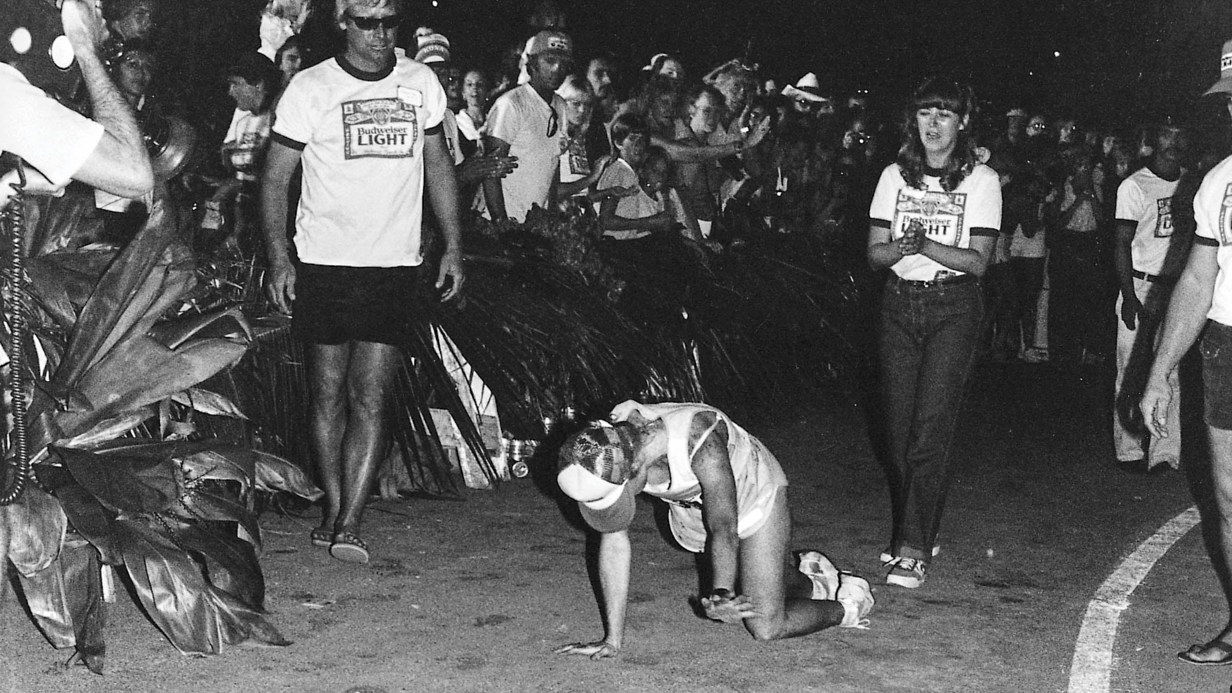 Black and white image of Julie Moss crawling toward the Ironman finish line with spectators watching