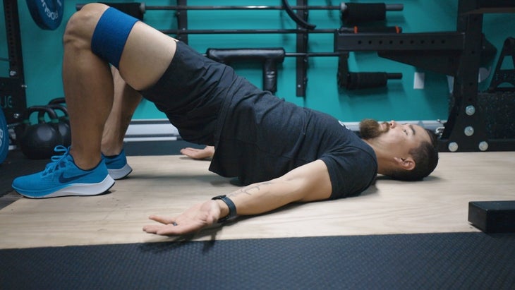 Man doing glute bridge with band around knees.