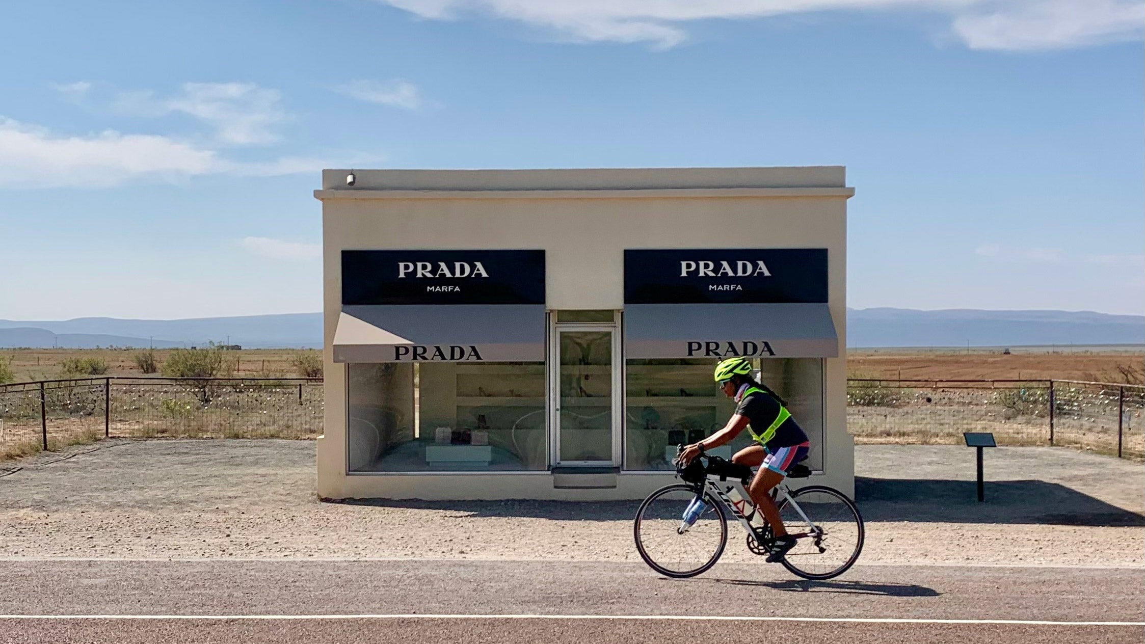Michelle Morton cycles past Prada Marfa, located  Northwest of Valentine, Texas. 