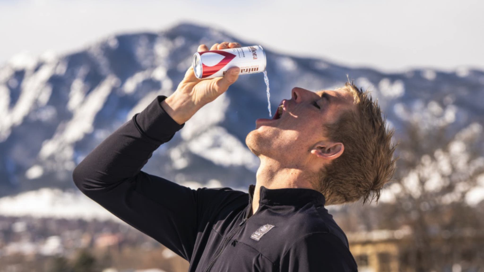 Sam Long outside, pouring a Miraflora drink in his mouth