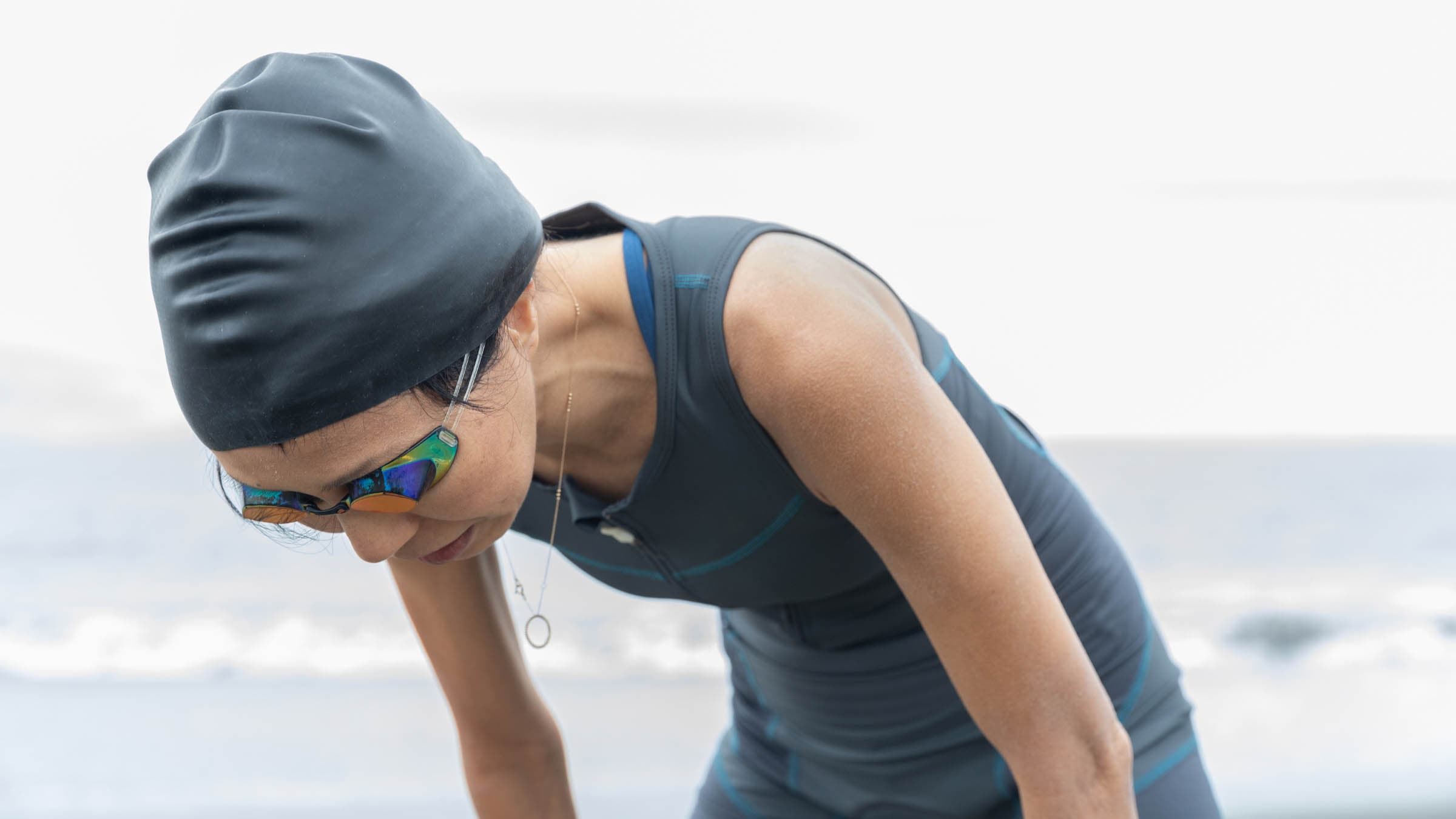 Woman dressed for swimming, bent over with her hands on her knees.