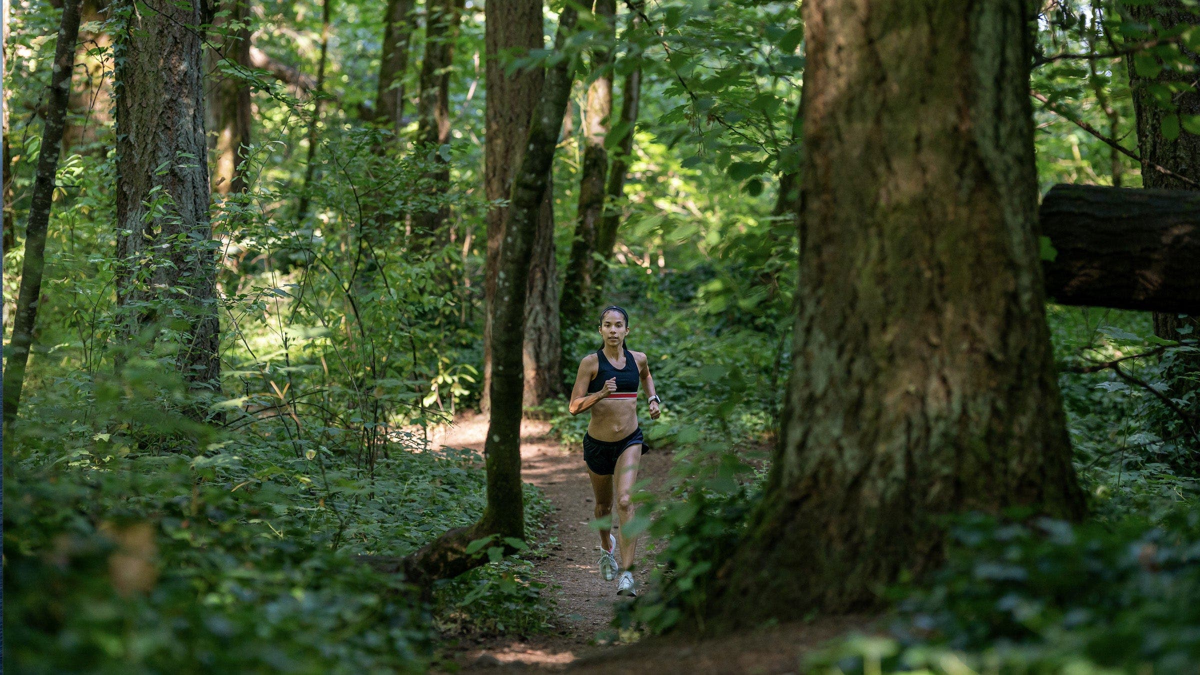 Women running on trail in dense forest