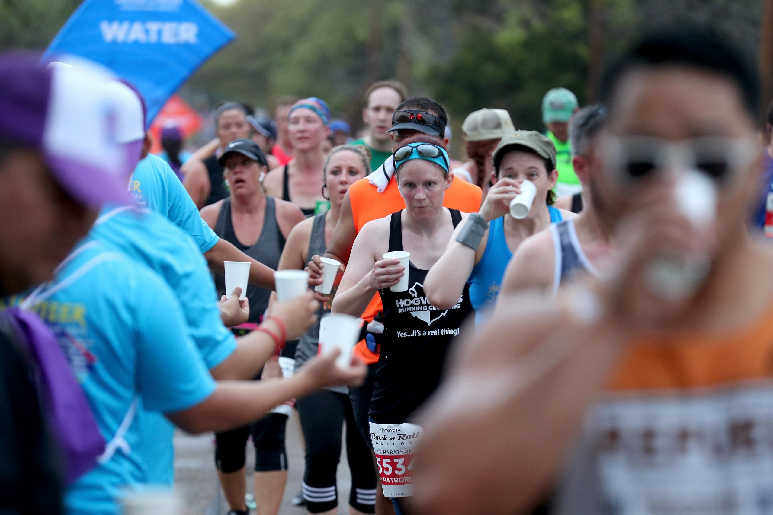 Runners grab cups at an aid station during the Rock n' Roll Dallas Half-Marathon