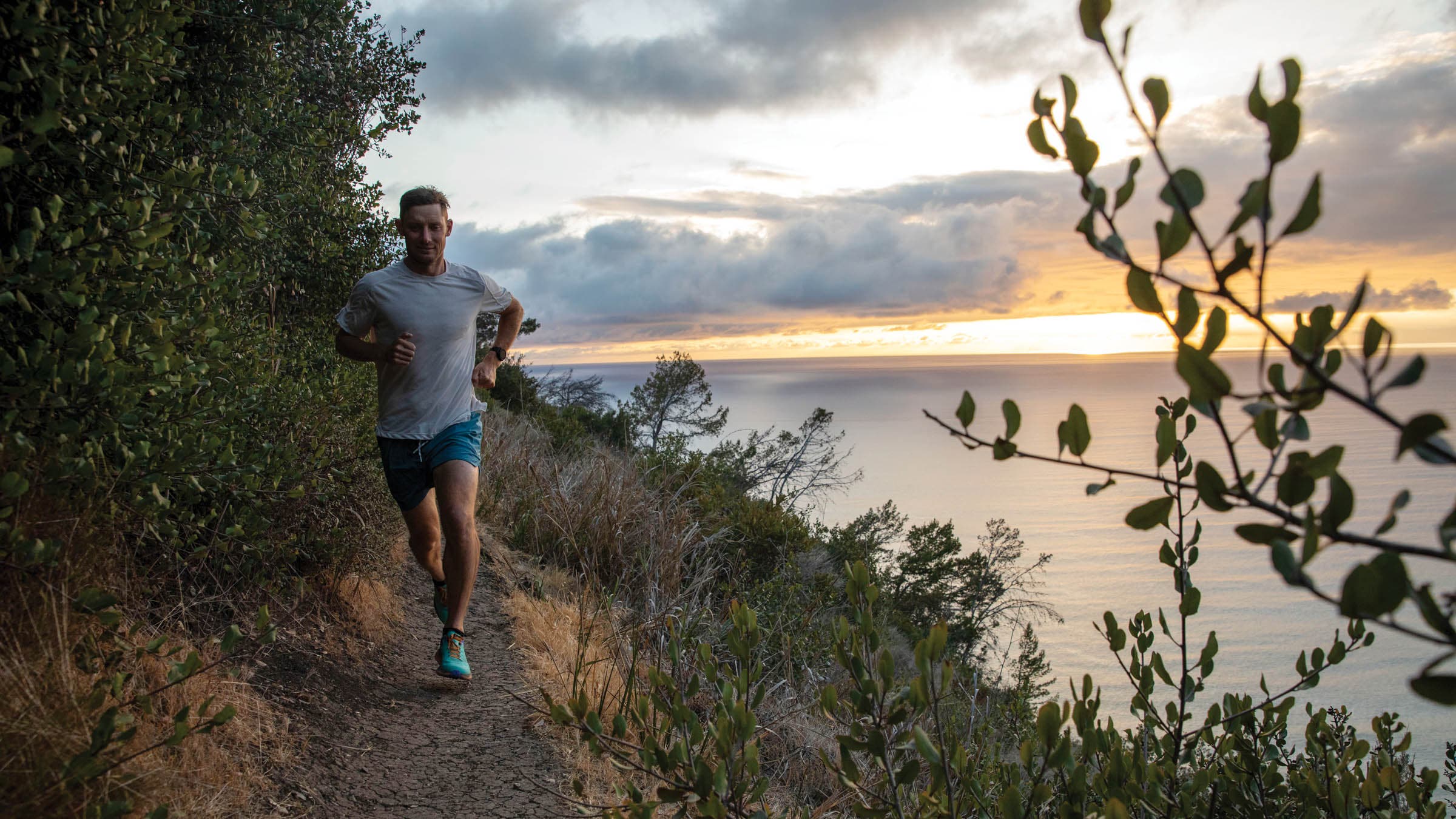 Man trail running along an oceanside cliff