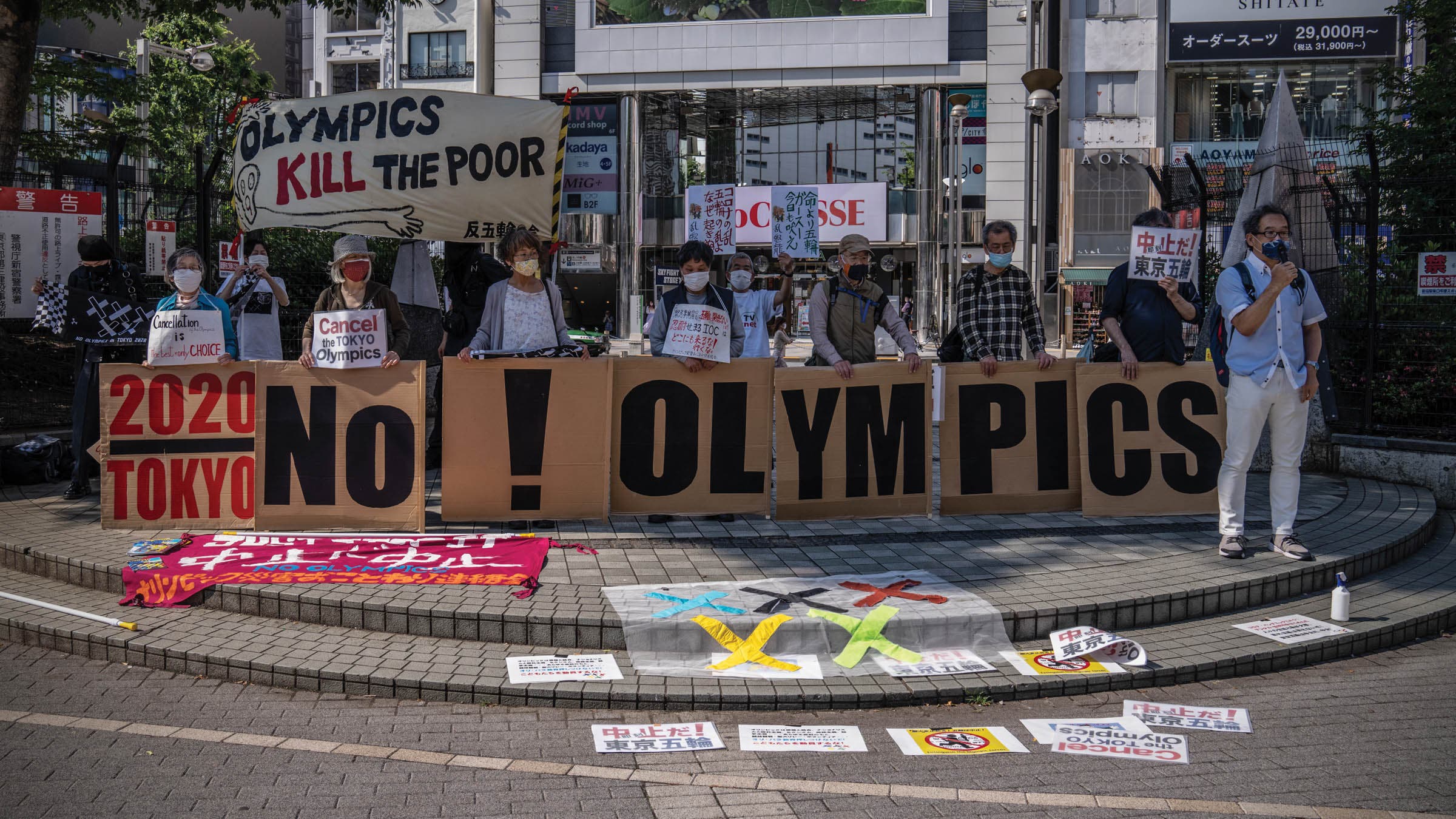 Protesters hold signs against holding the Tokyo Olympics