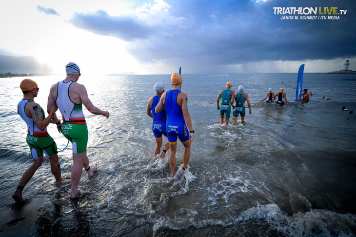 Athletes in the visually-impaired paratriathlon race enter the water with their guides.
