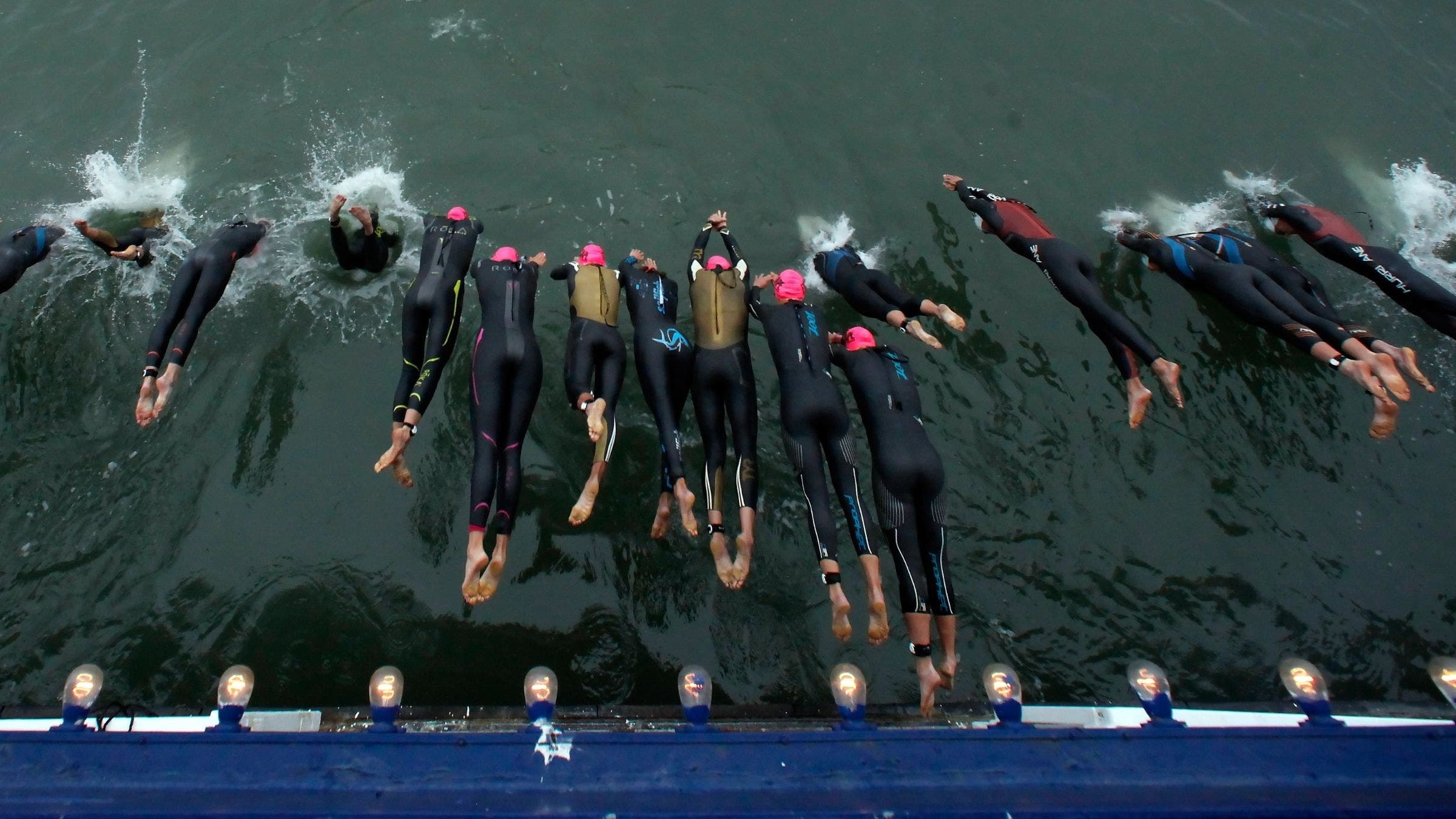 overhead shot looking down of women jumping off ferry into San Francisco Bay in wetsuits for Escape from Alcatraz Triathlon