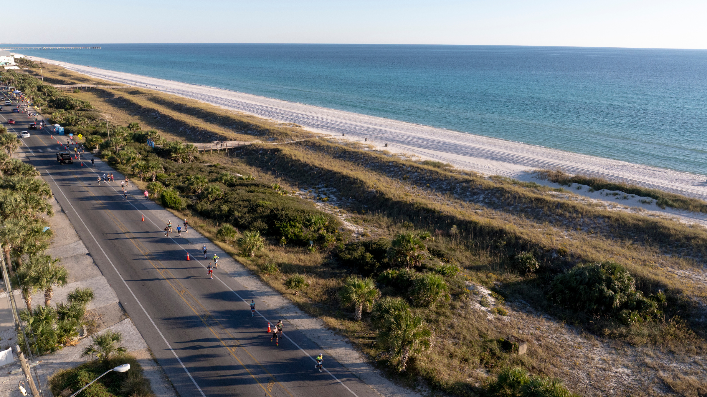 aerial shot of cyclists riding in direct sun on road along Florida coastline