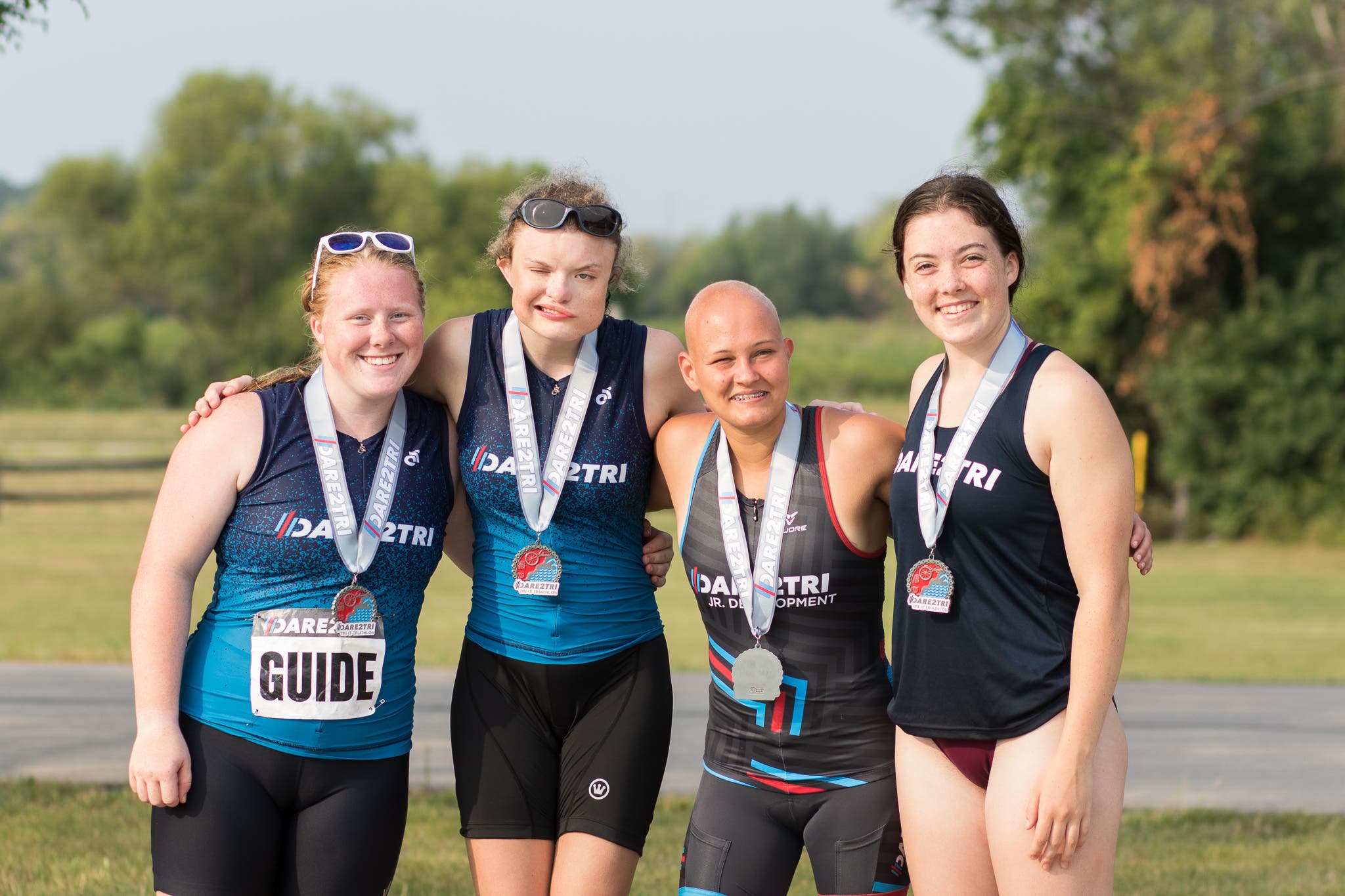 Dare2Tri athletes smile while posing with their arms around each other.