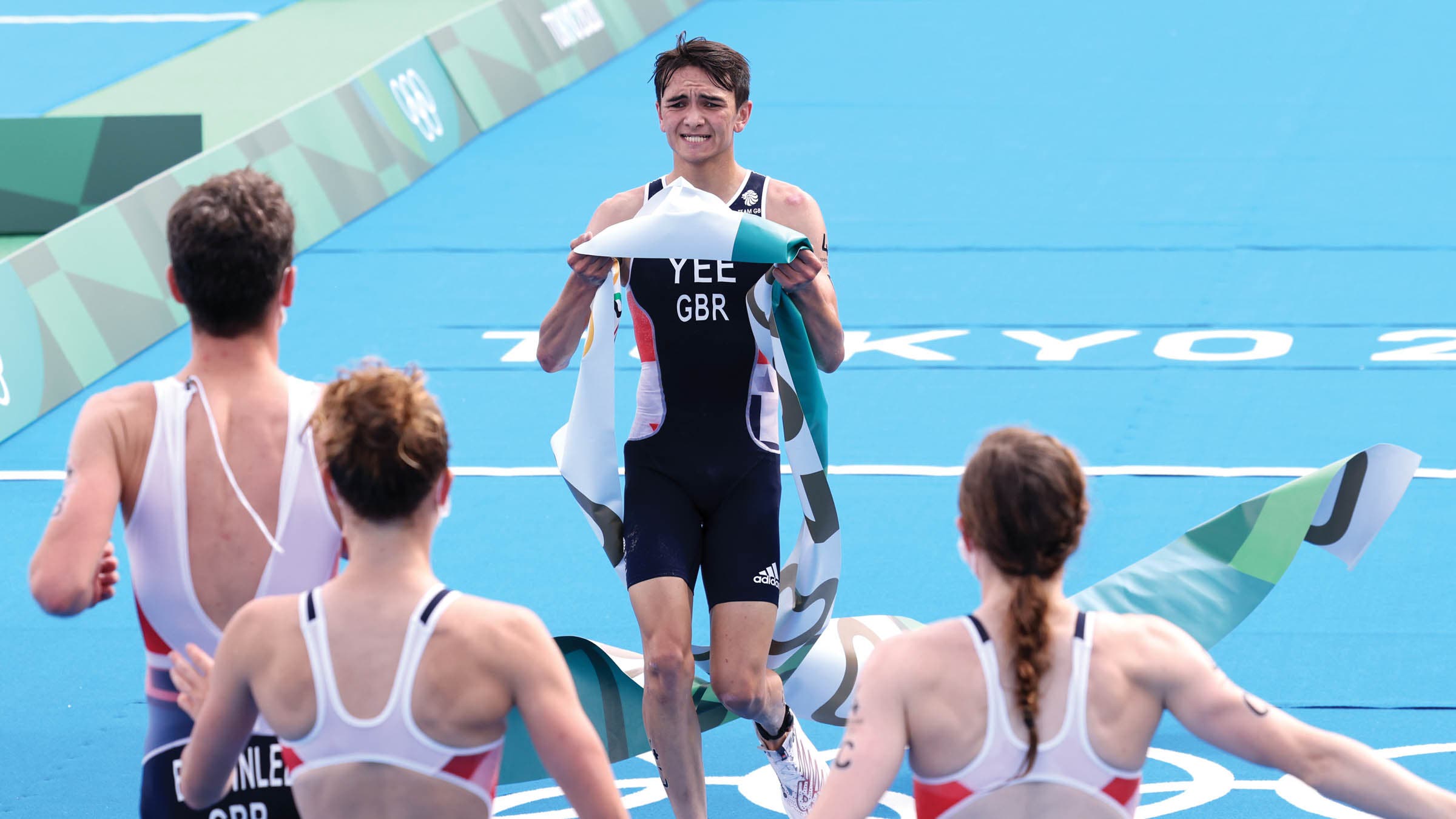 Alex Yee celebrating with finish line tape in his hands