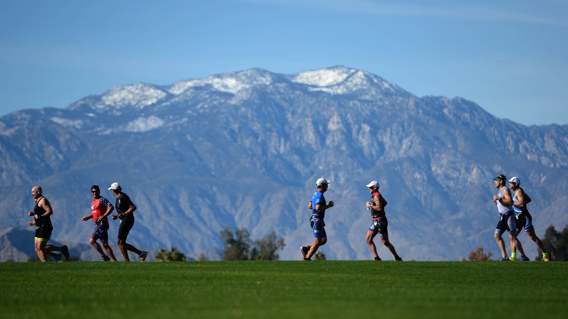 Triathletes run in front of a majestic mountain backdrop at Ironman 70.3 Indian Wells.
