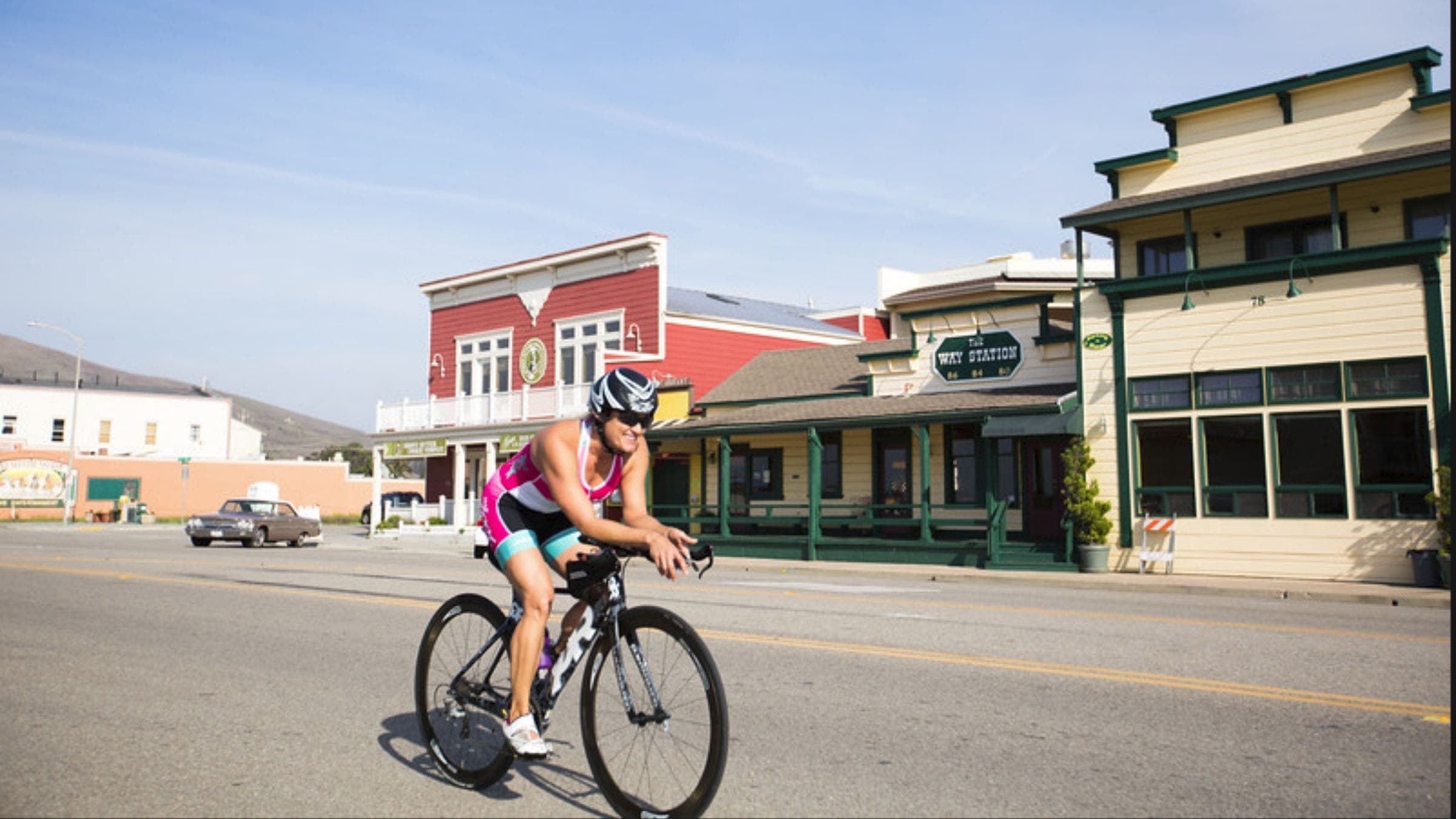 A woman on a triathlon bike smiles as she rides through the Morro Bay Triathlon.