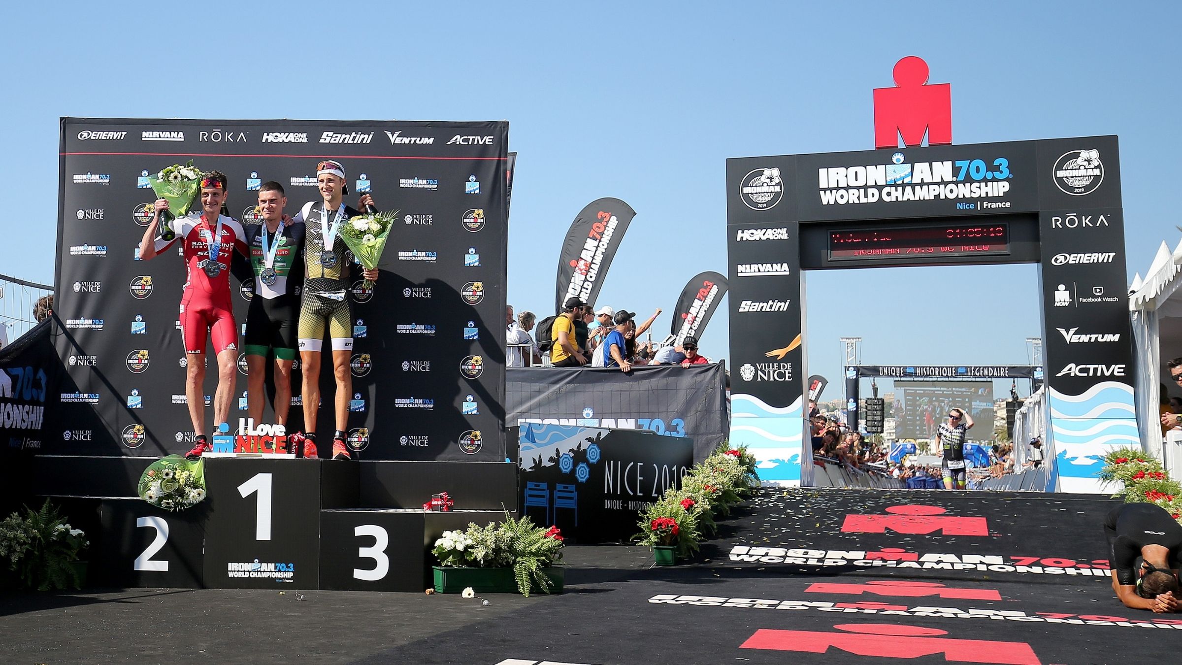 Three men stand atop a podium at Ironman 70.3 World Championships.
