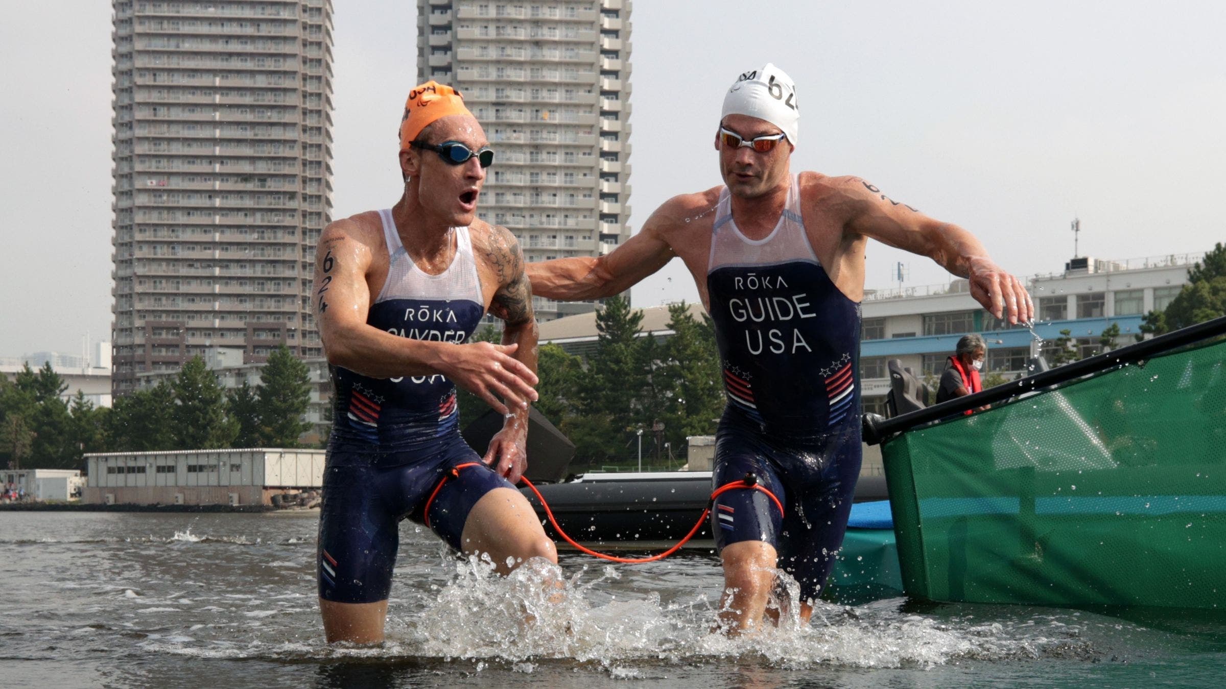 A blind triathlete and his guide exit the water at the paralympic triathlon