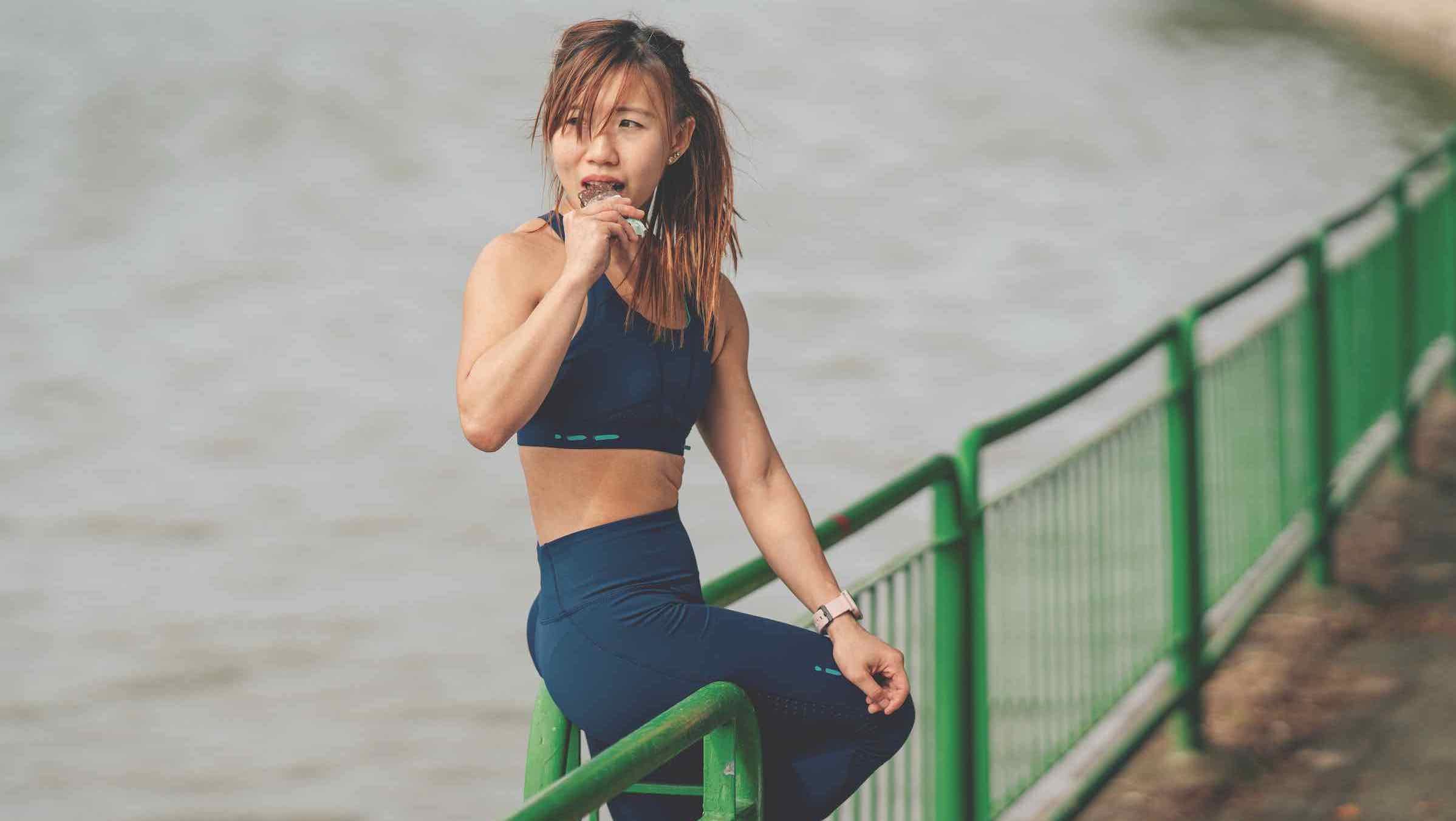 Asian woman eating an energy bar between exercise