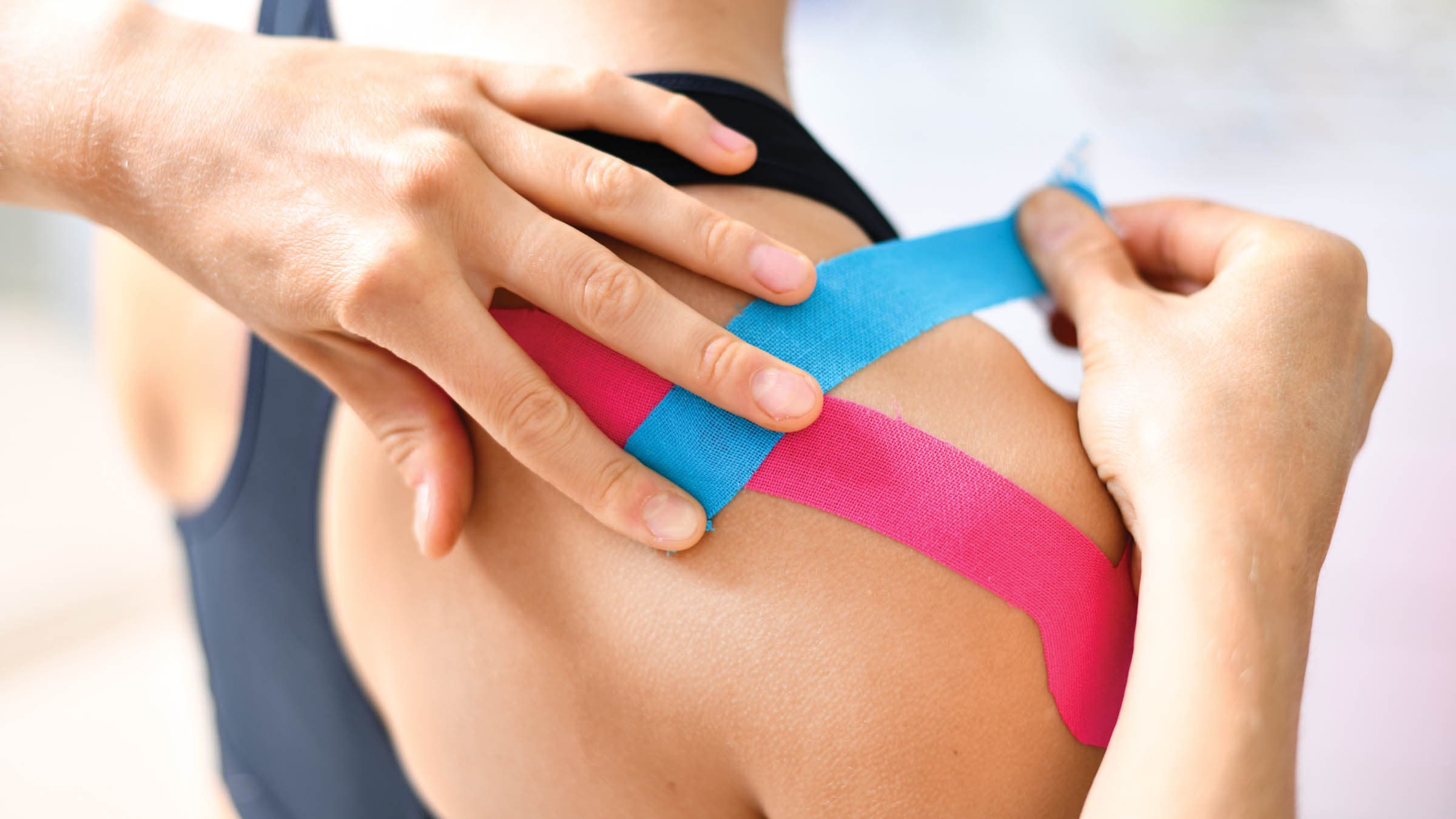 Kinesiology taping treatment with blue and pink tape on athlete