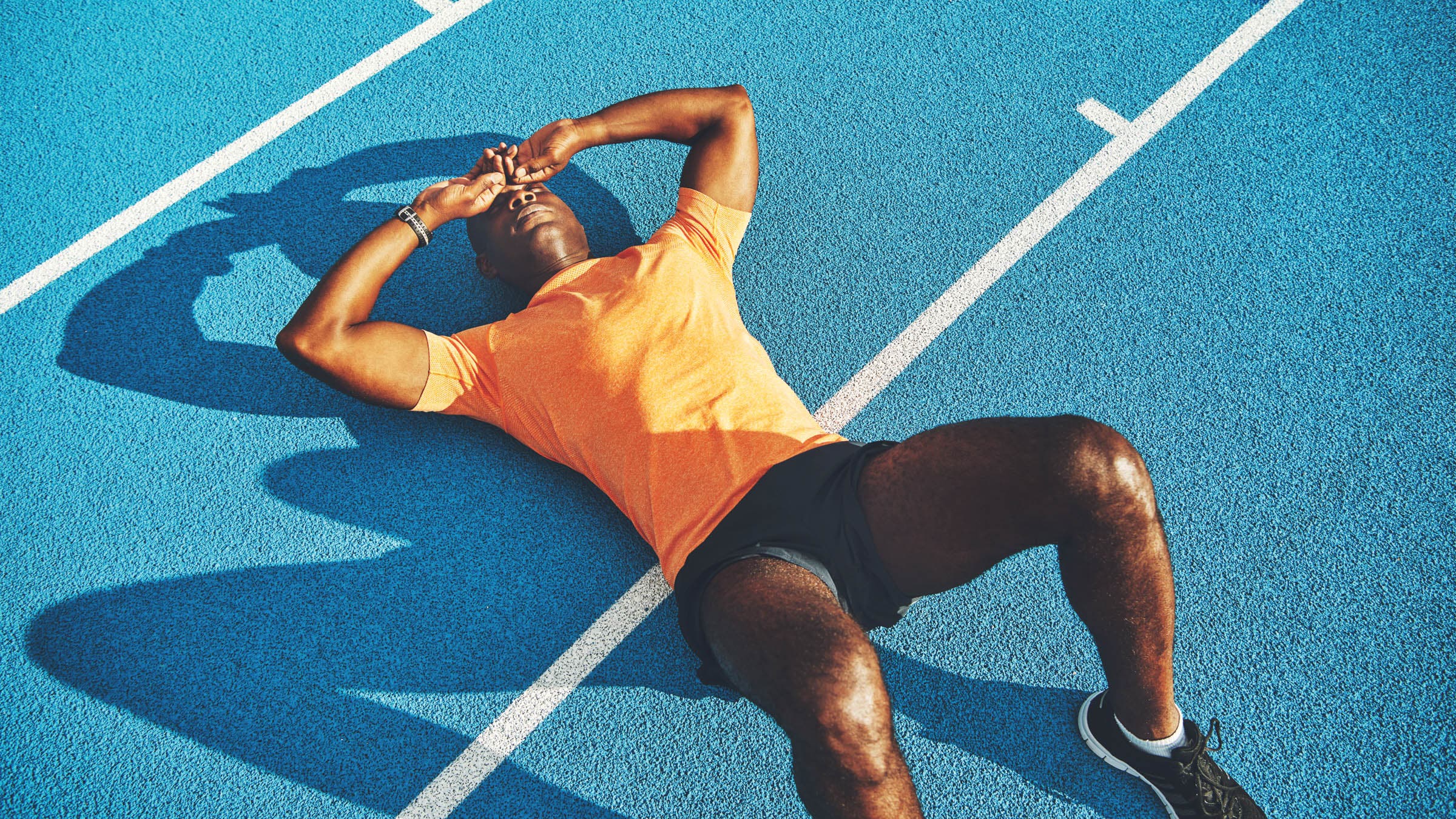 Exhausted young man lying on the lanes of a running track