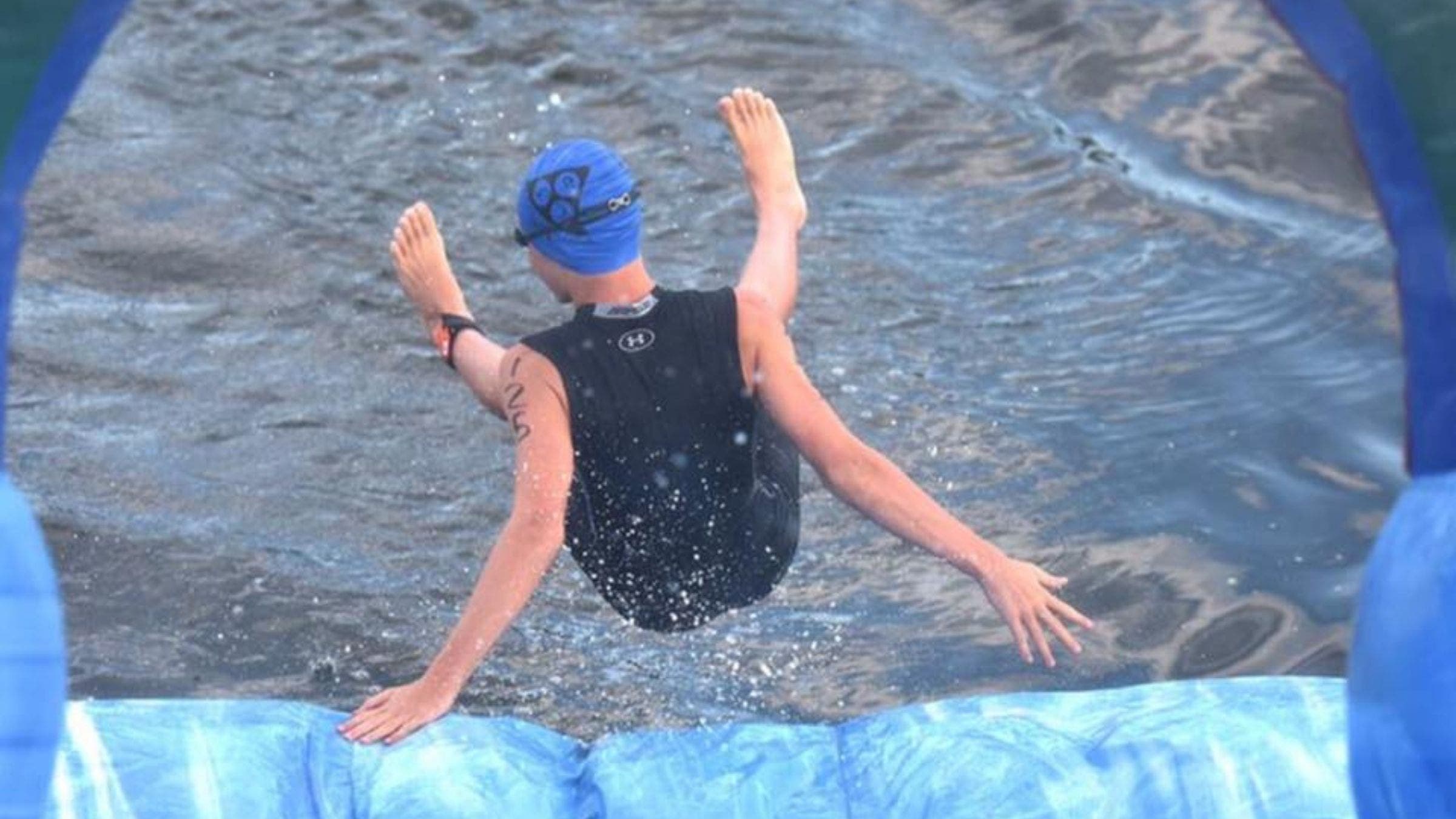 An athlete slides down the giant rainbow inflatable into the river to start the Chattahoochee Challenge Sprint Triathlon.
