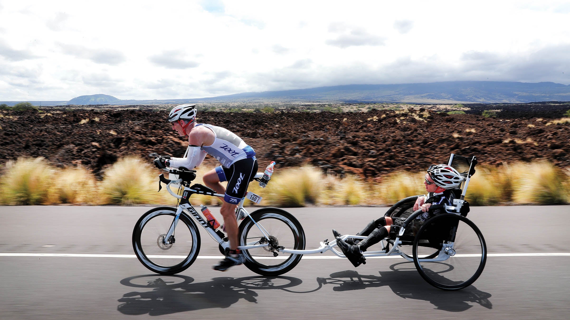 Jeff Agar riding a bike pulling Johnny Agar behind