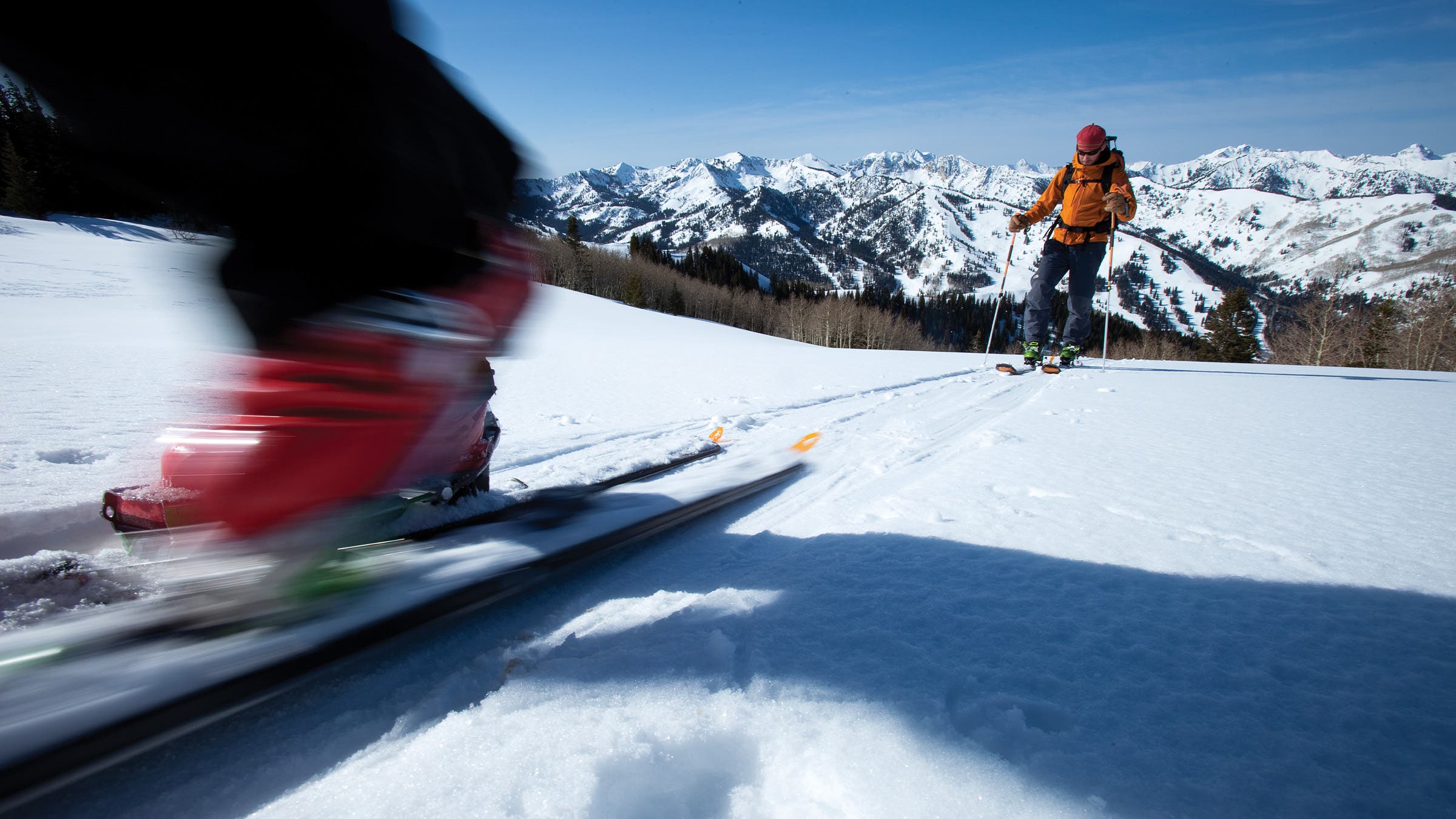 Two skiers on a flat section fly by the camera