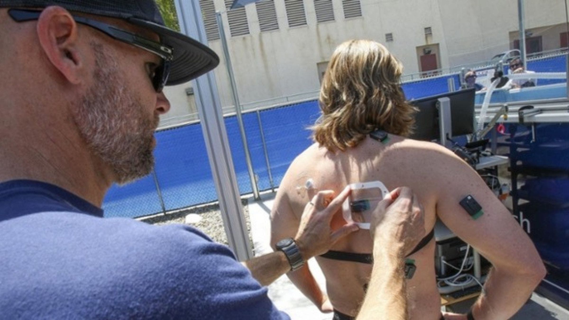 A scientist attaches sensors to the body of a swimmer during wetsuit testing at the Newcomer Lab.