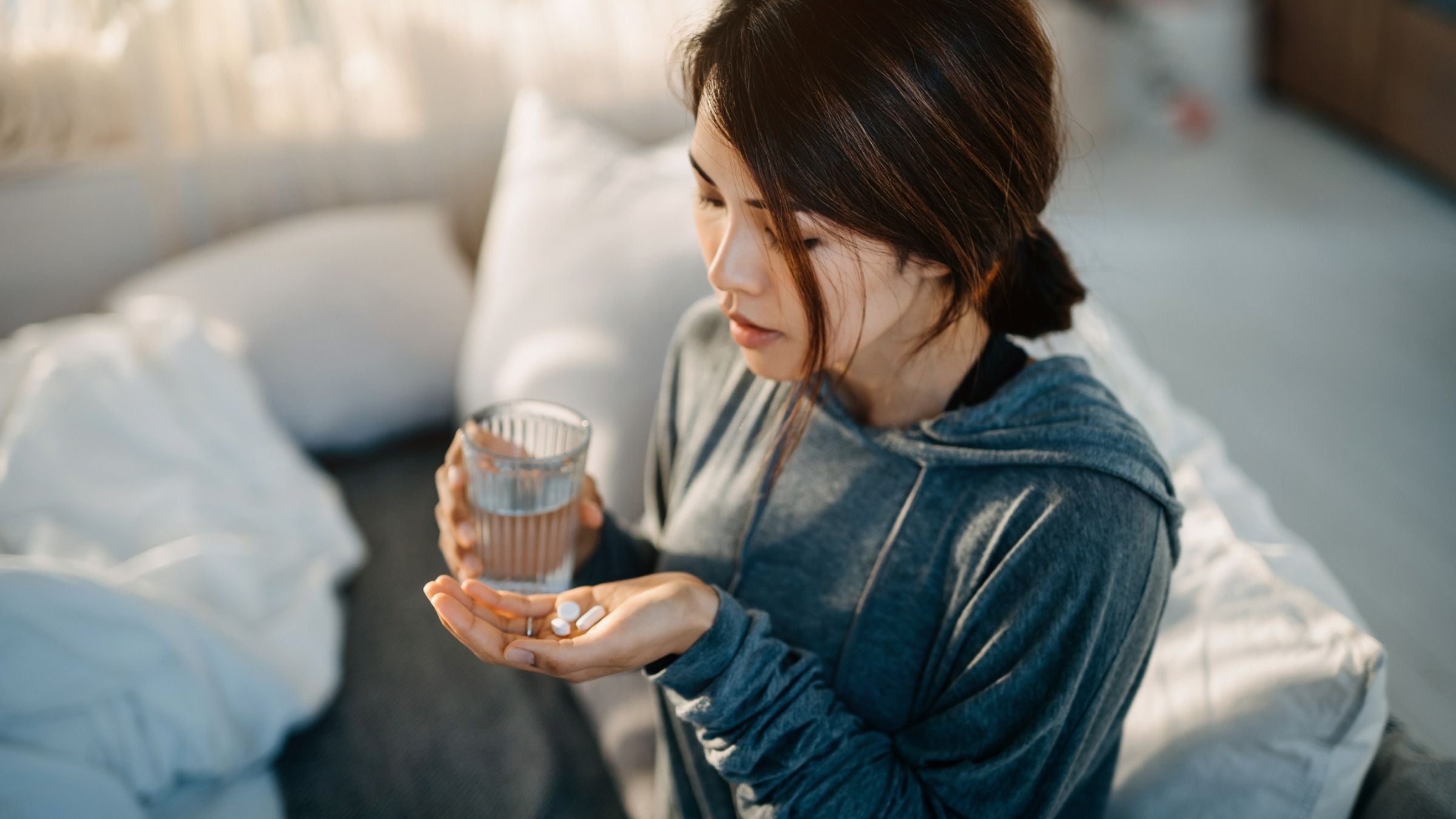 A woman holds a handful of supplements.