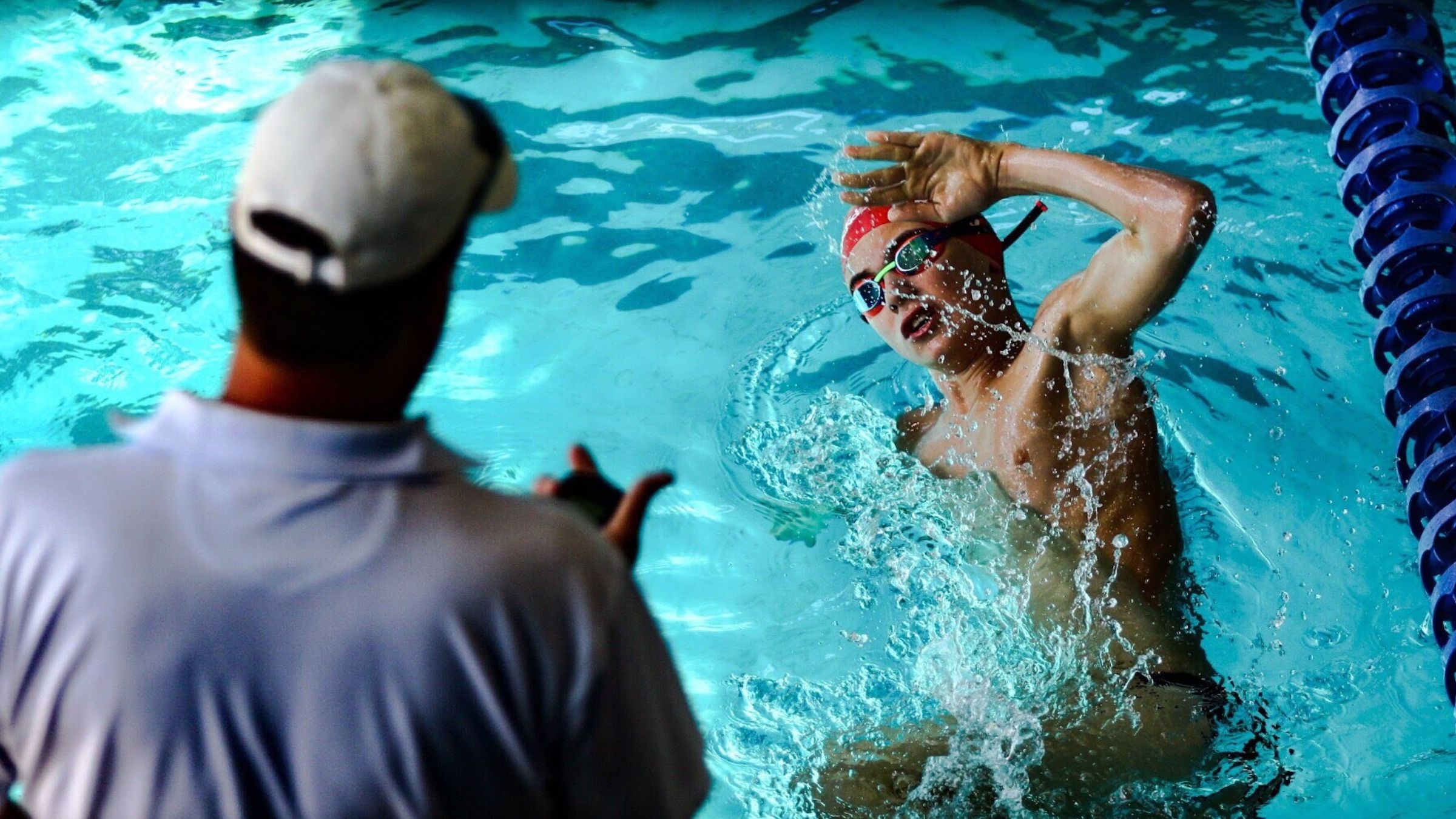 A coach gives a triathlete with autism splits in the pool.