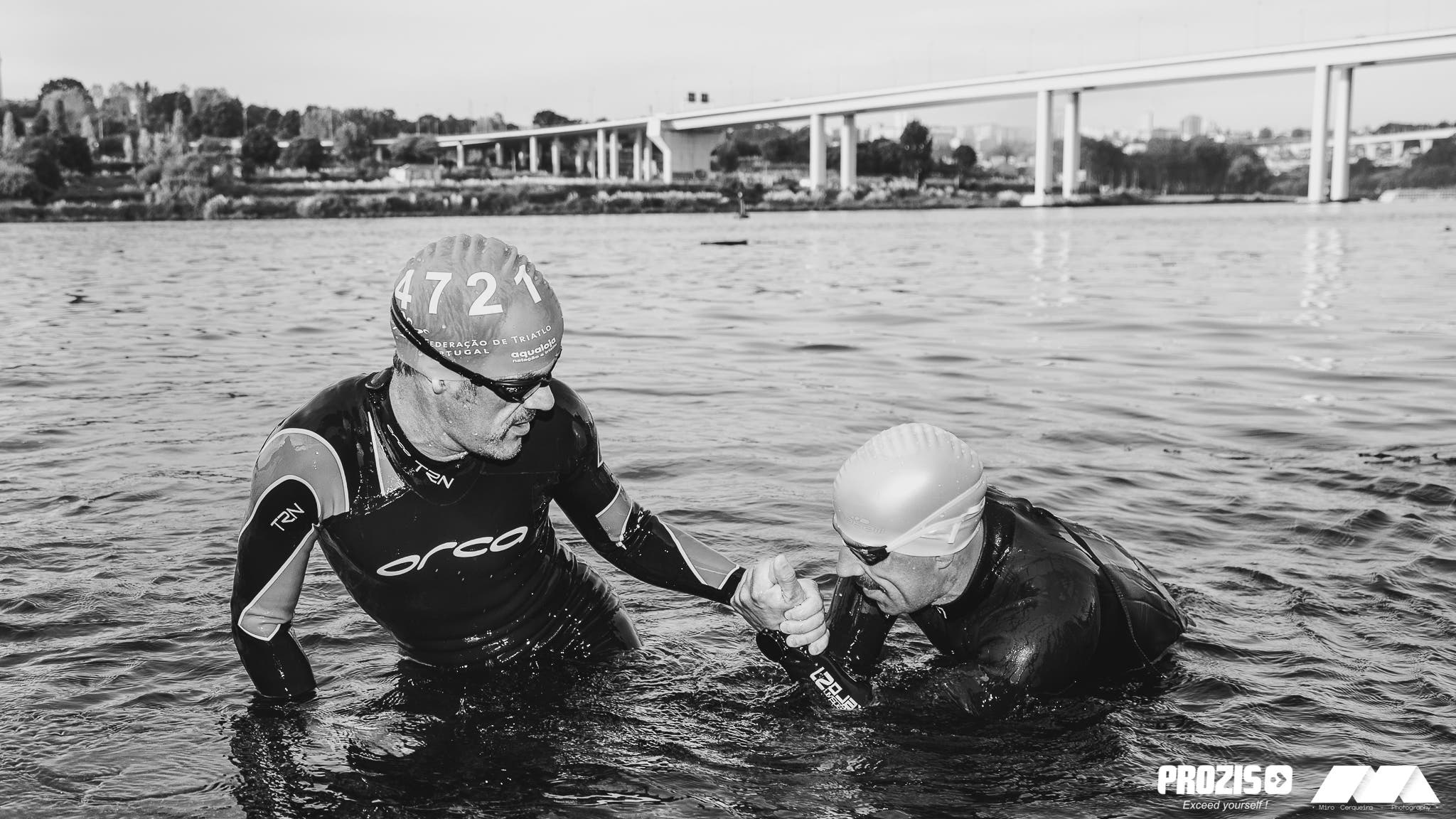 Two athletes at the Spirit of 78 Triathlon help each other out of the swim.