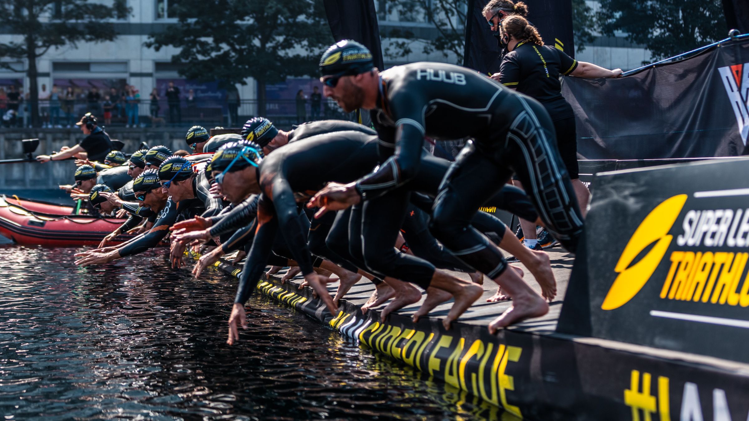 A row of triathletes jumping into the water, how to watch super league london livestream