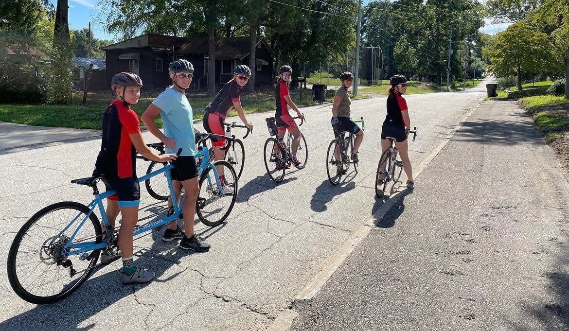 Maggie Peters, a triathlete with a visual impairment, rides a tandem bike with a guide while on a group ride with the Newberry College triathlon team