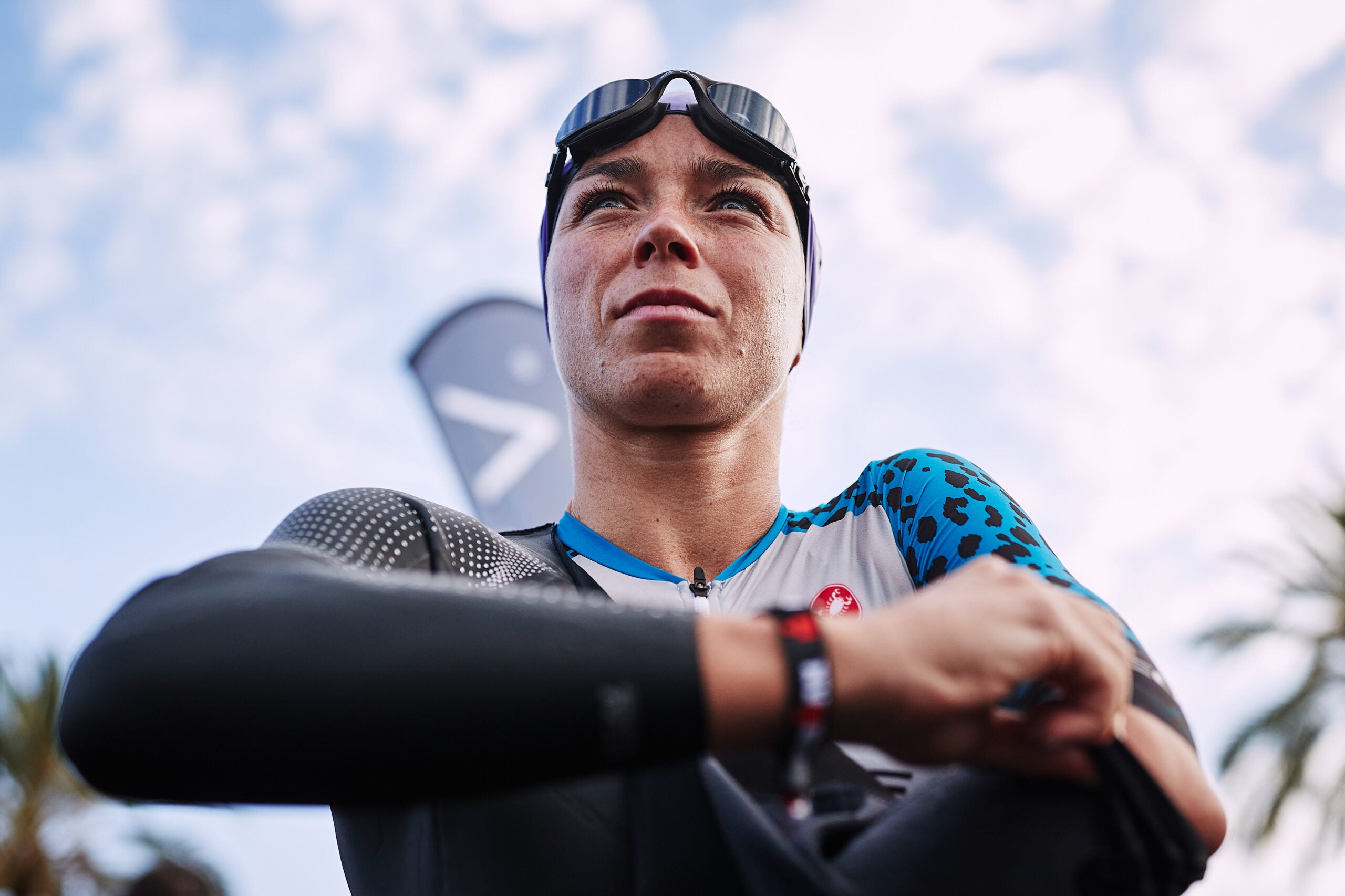 A triathlete zips into a wetsuit while wondering How much faster do you swim with a wetsuit?