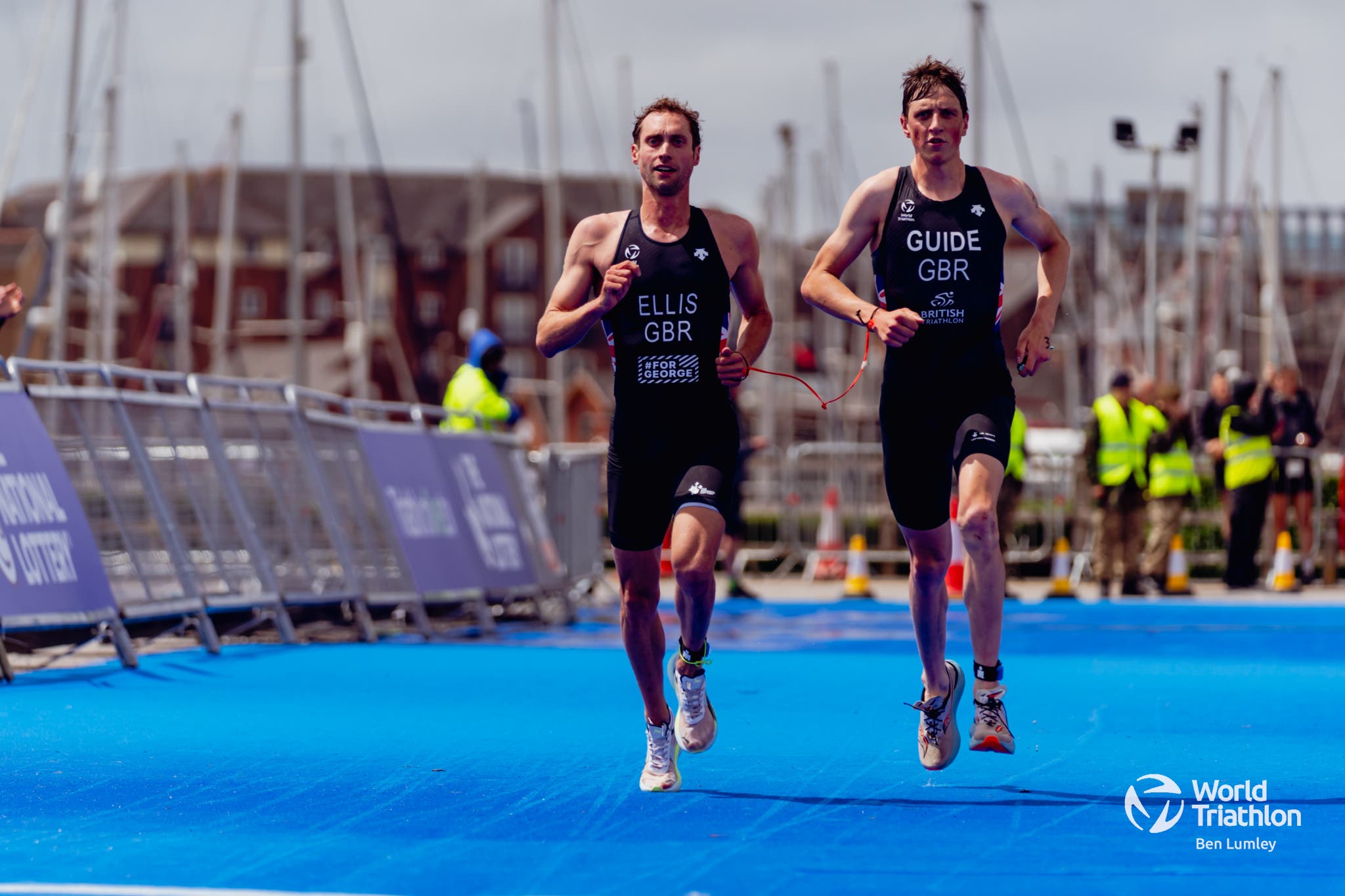 A triathlete with visual impairment races down the finish chute with his guide.