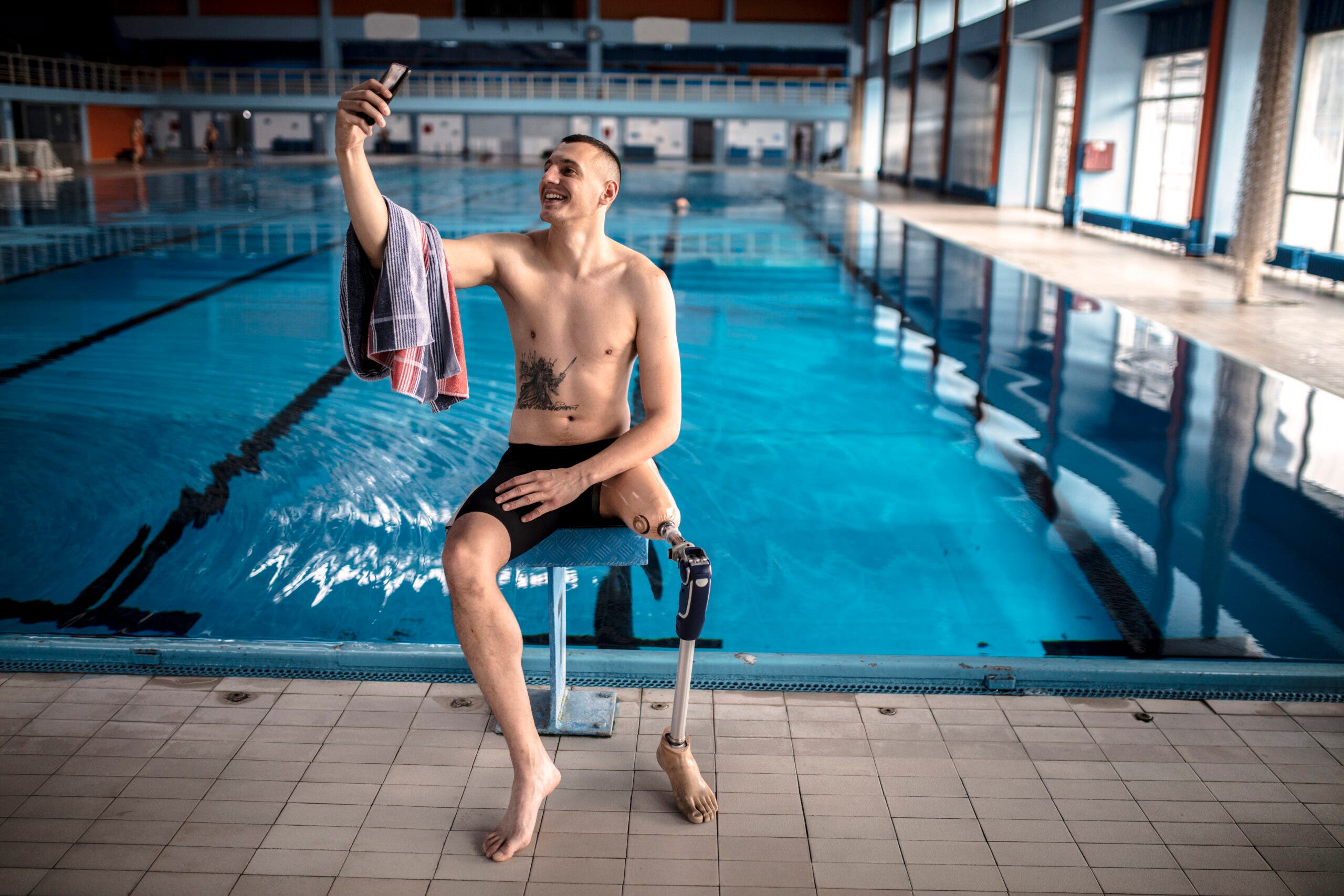Man using phone at pool swim workout.