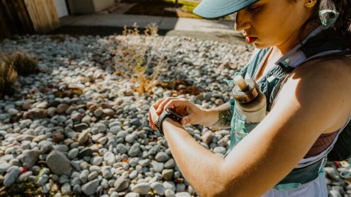 A female runner looks at her watch while wondering How does my smartwatch determine heart rate zones