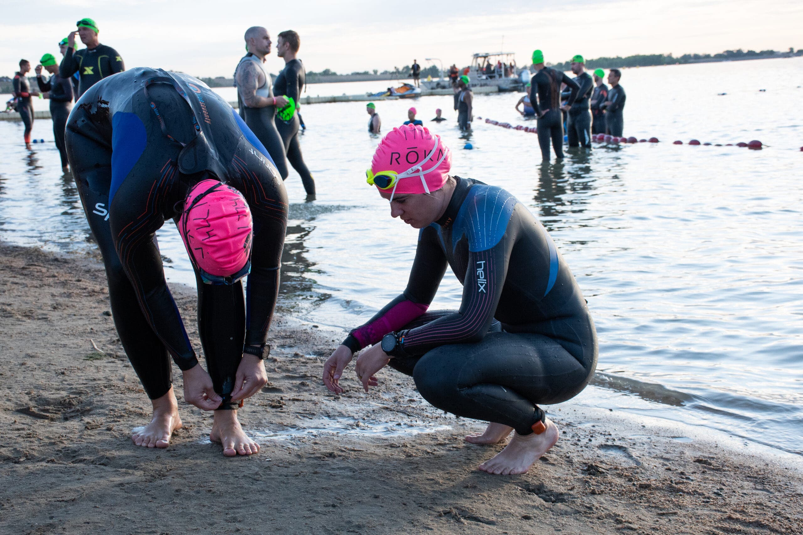 Triathletes make adjustments to putting on a triathlon wetsuit.