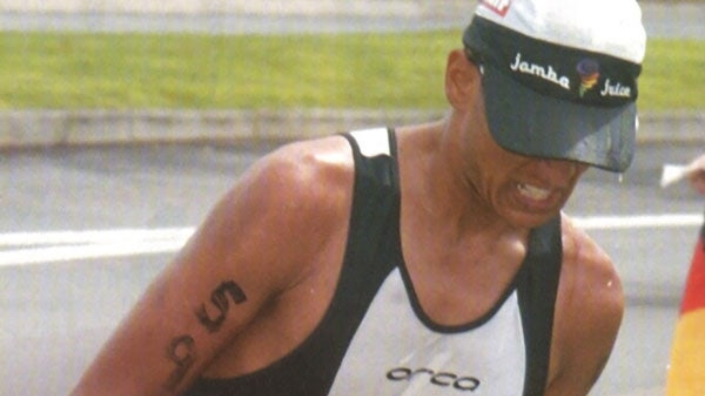 Man in tri singlet and hat grimaces in Ironman World Championship