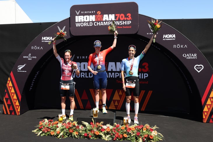 Kat Matthews (L), Taylor Knibb (C) and Ashleigh Gentle (R) celebrate on the podium at the 2024 Ironman 70.3 World Championship in Taupo, New Zealand.