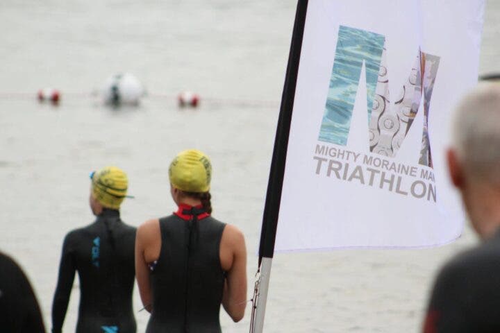 Two athletes wait on the shore for their turn to start the swim at the Mighty Moraine Spring Multisport Festival.