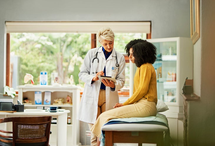 doctor talking to female patient sitting on chair in doctor's office