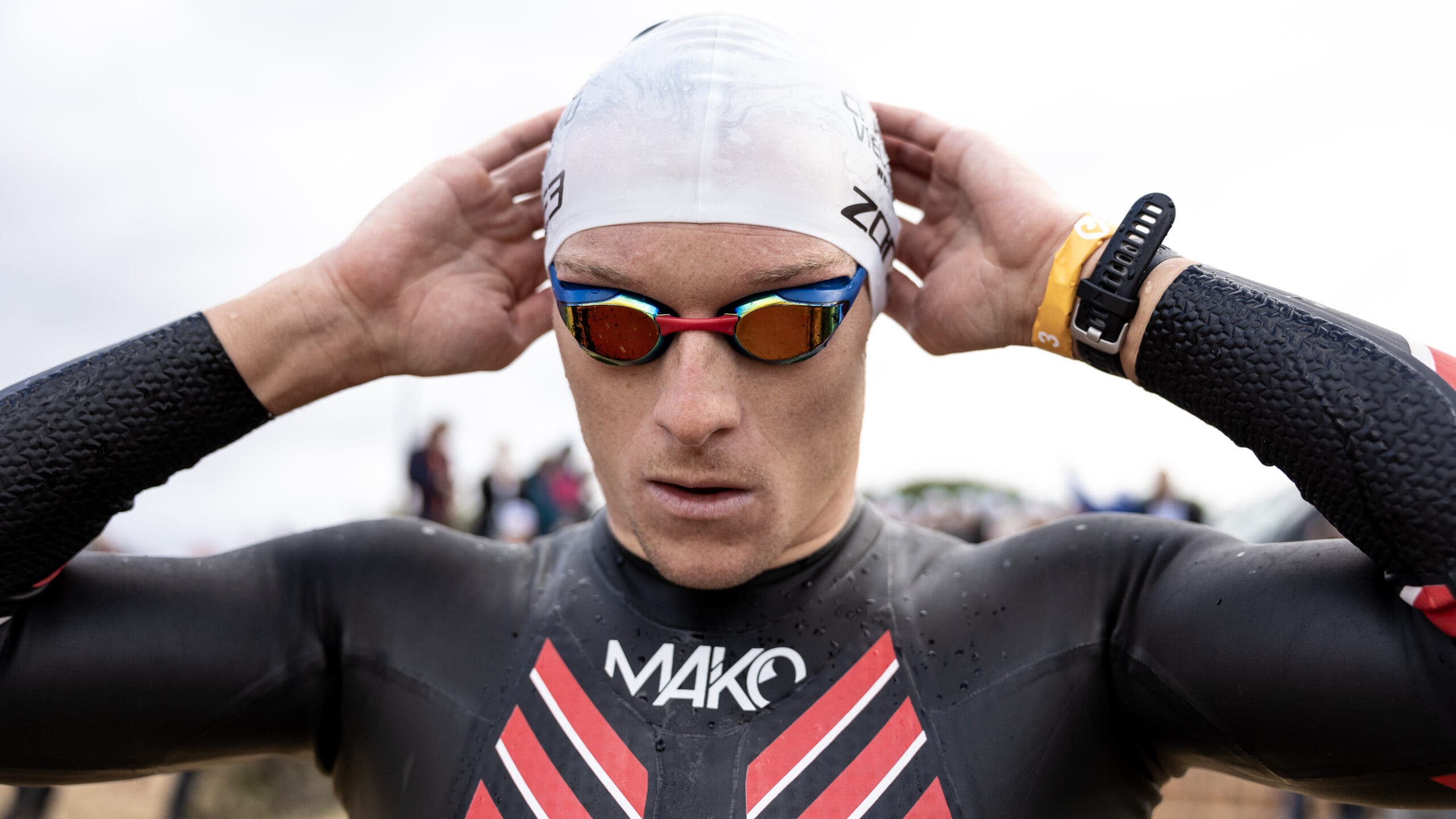An athlete prepares for open water swimming using anti-fog goggles.