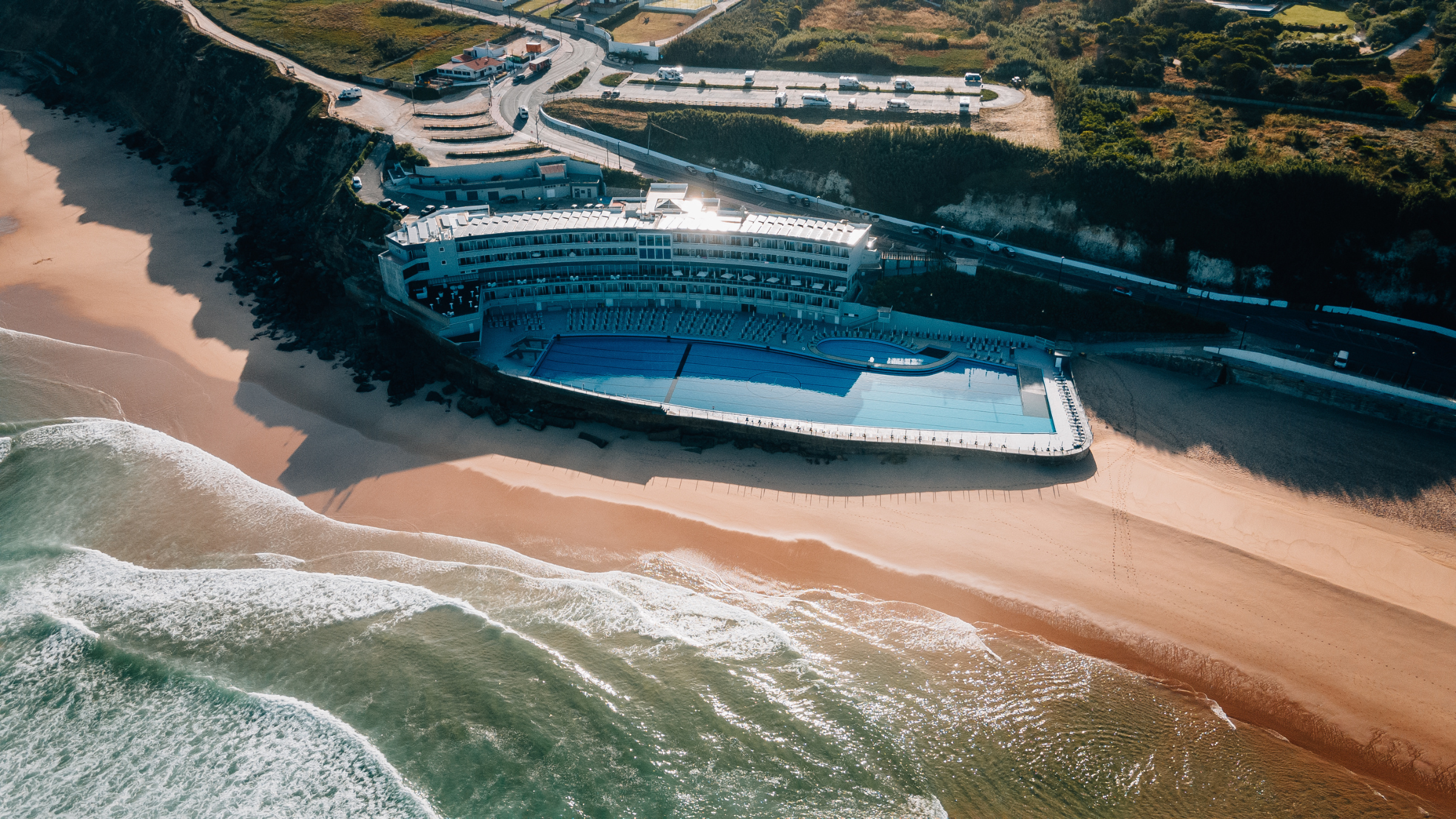 An overhead shot of a huge hotel pool next to the hotel and the beach