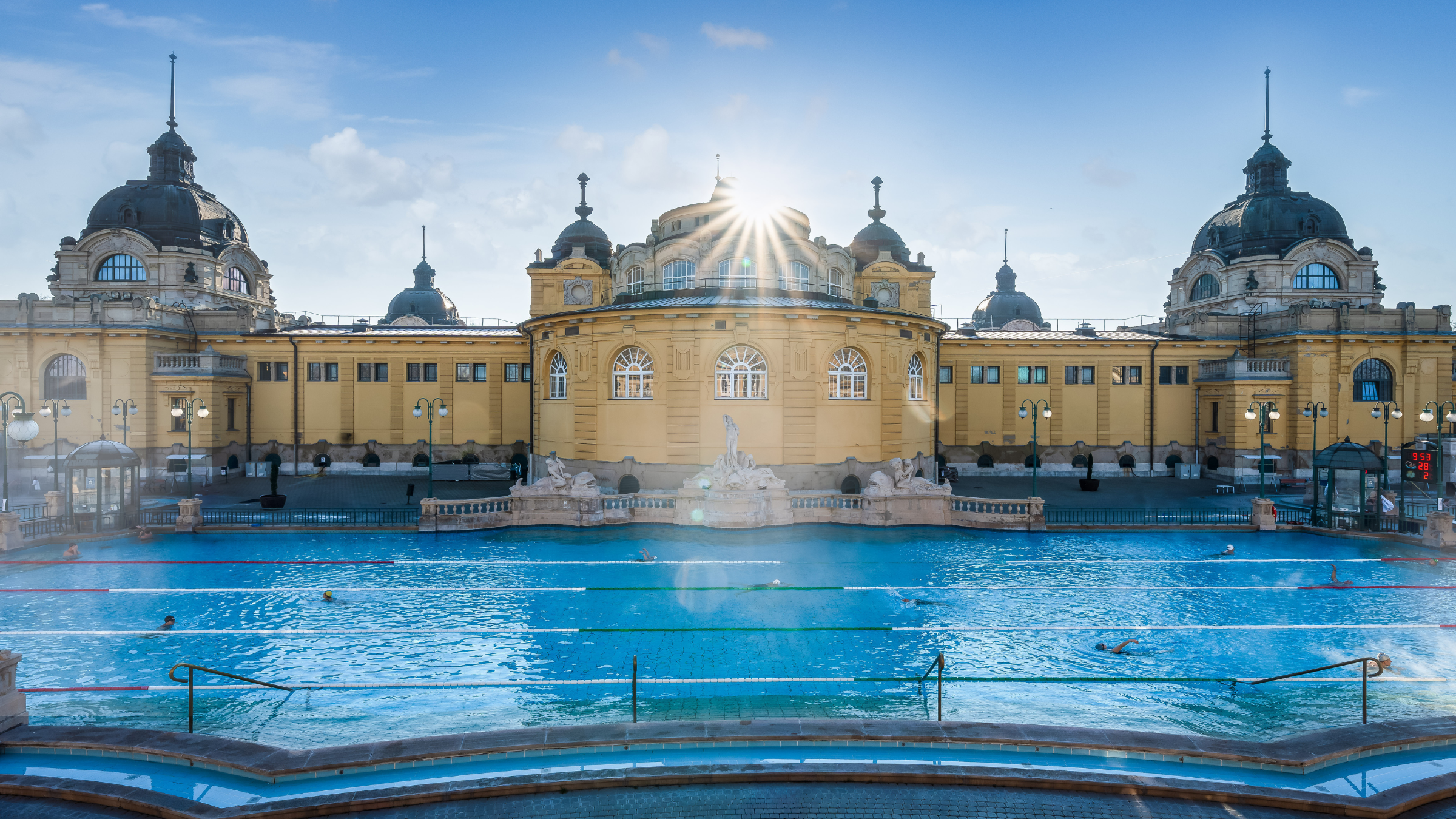 Interesting photo with a swimming pool in the foreground, a 100-year-old yellow building in the background, and light coming from the roof