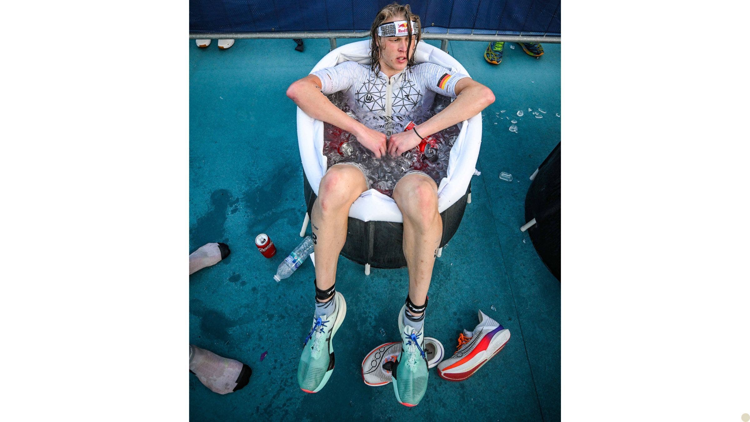 A tired looking athlete sits in a cold plunge pool after a triathlon.