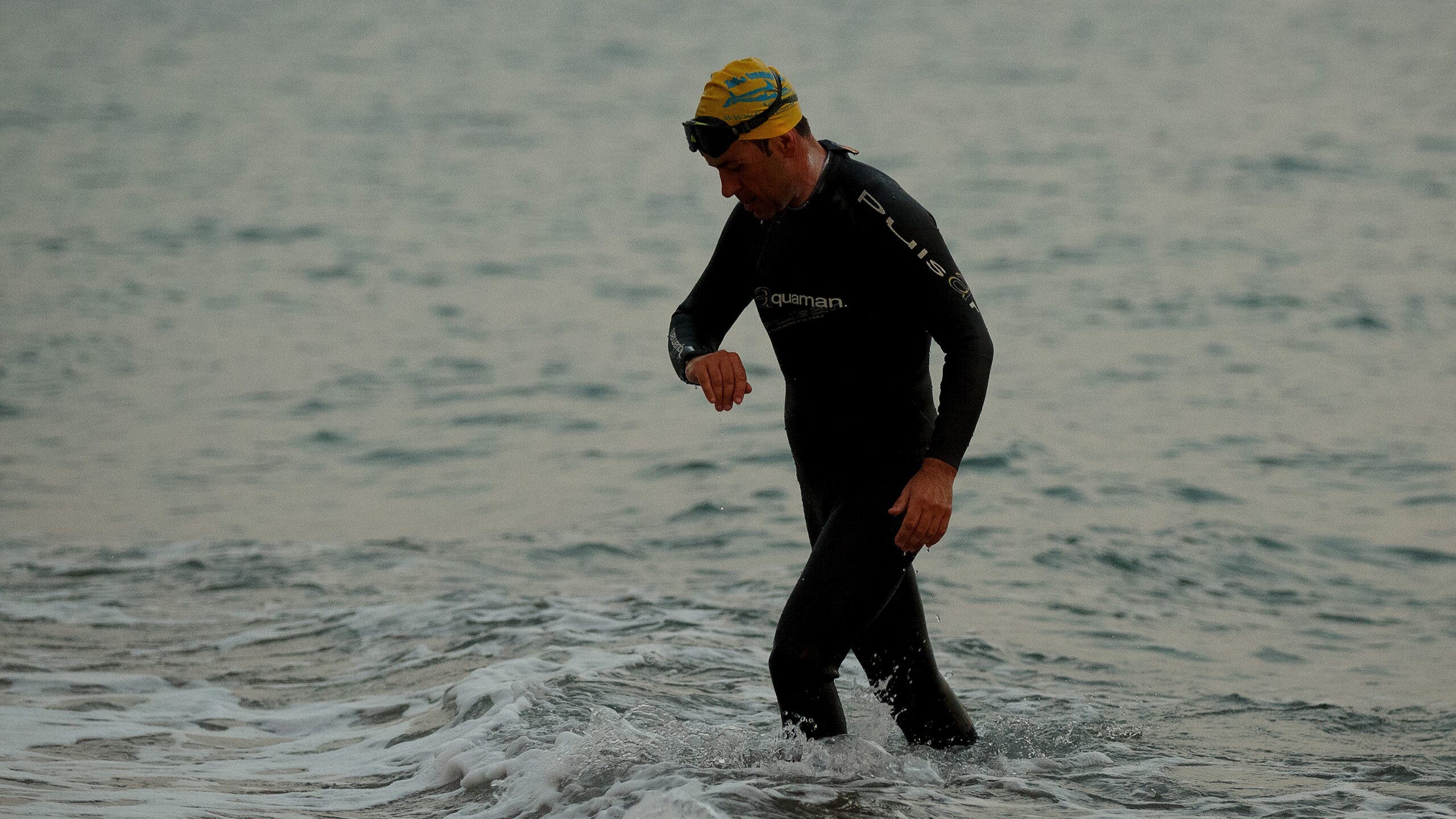 An athlete finishes swimming and checks his watch for calorie burn data.